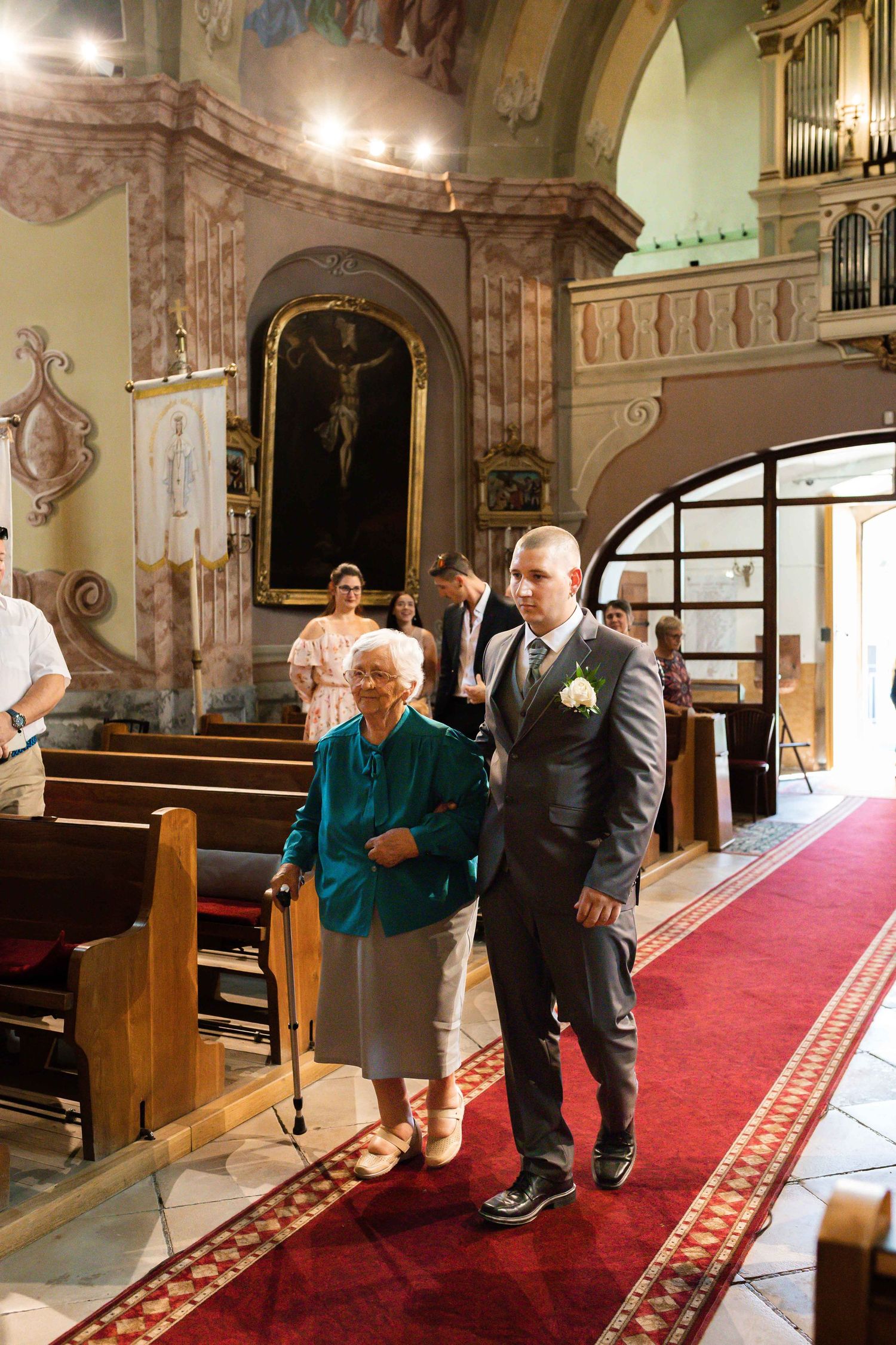 A couple shares an intimate moment in a historic church with ornate architecture and a red carpet aisle.