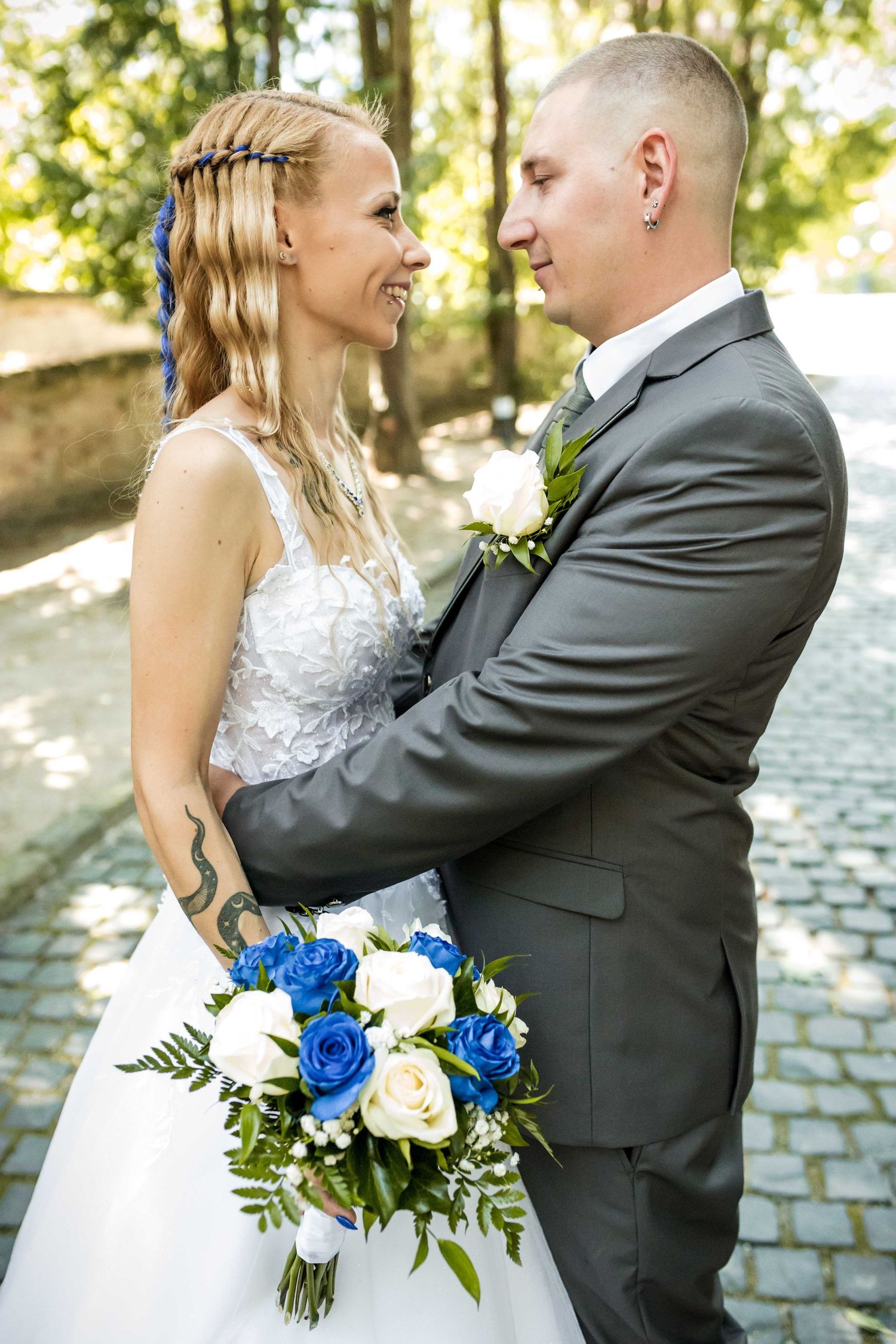 A newlywed couple shares a joyful moment on their wedding day with a bouquet of blue and white roses.