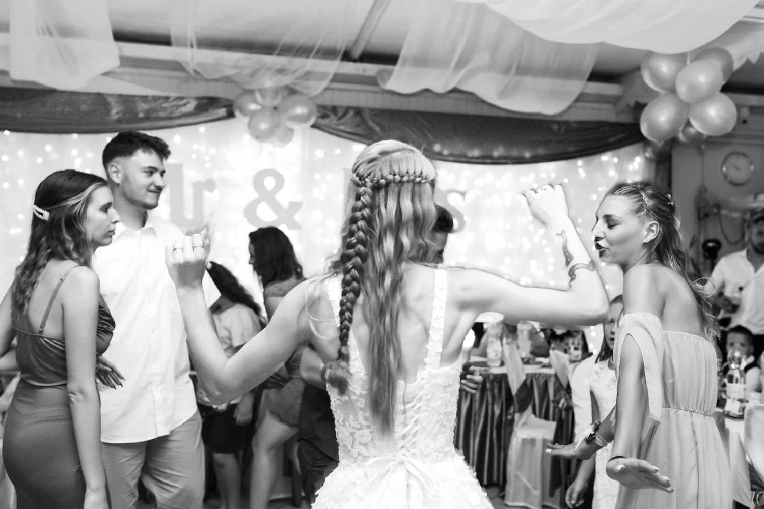 Wedding guests dancing and celebrating on the dance floor at an indoor reception venue.