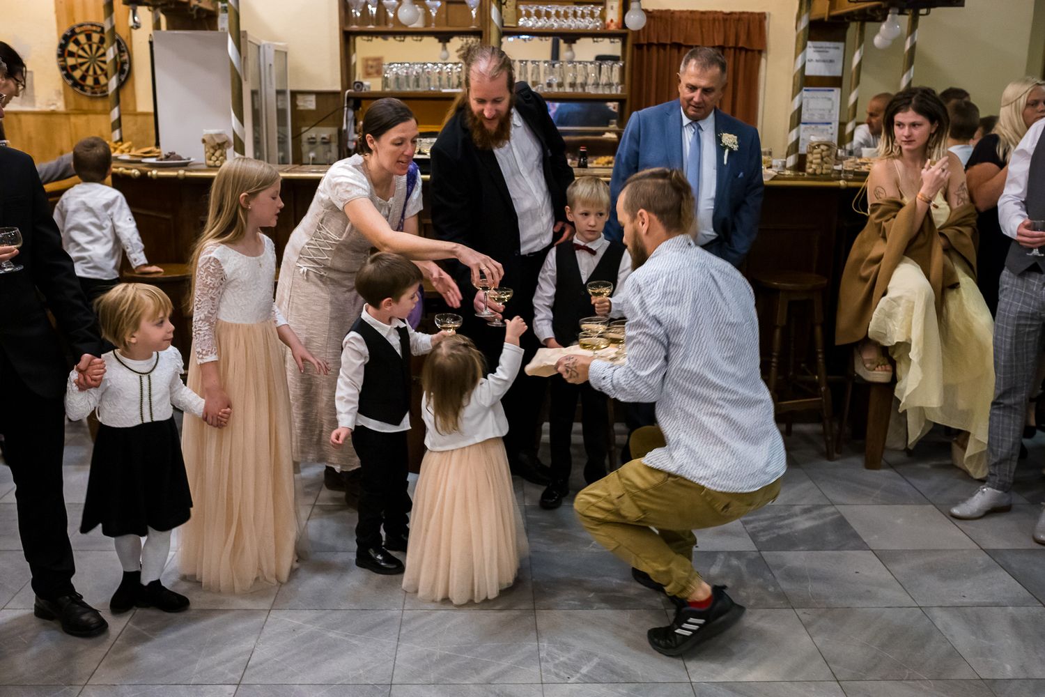 Wedding party dances together in a rustic reception venue with wooden beams and string lights.