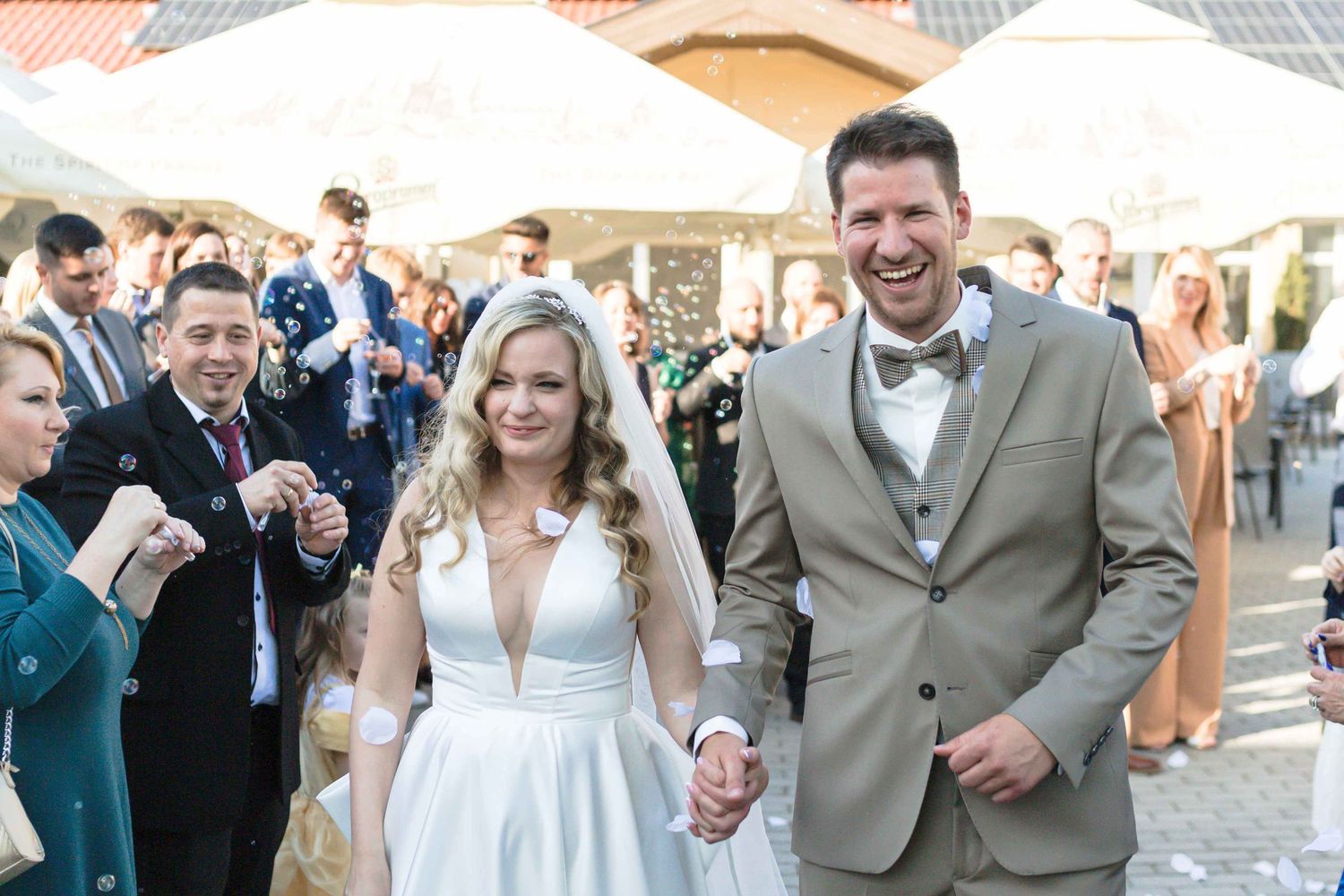 Happy wedding couple and guests celebrate with sparklers during outdoor evening reception at rustic venue.