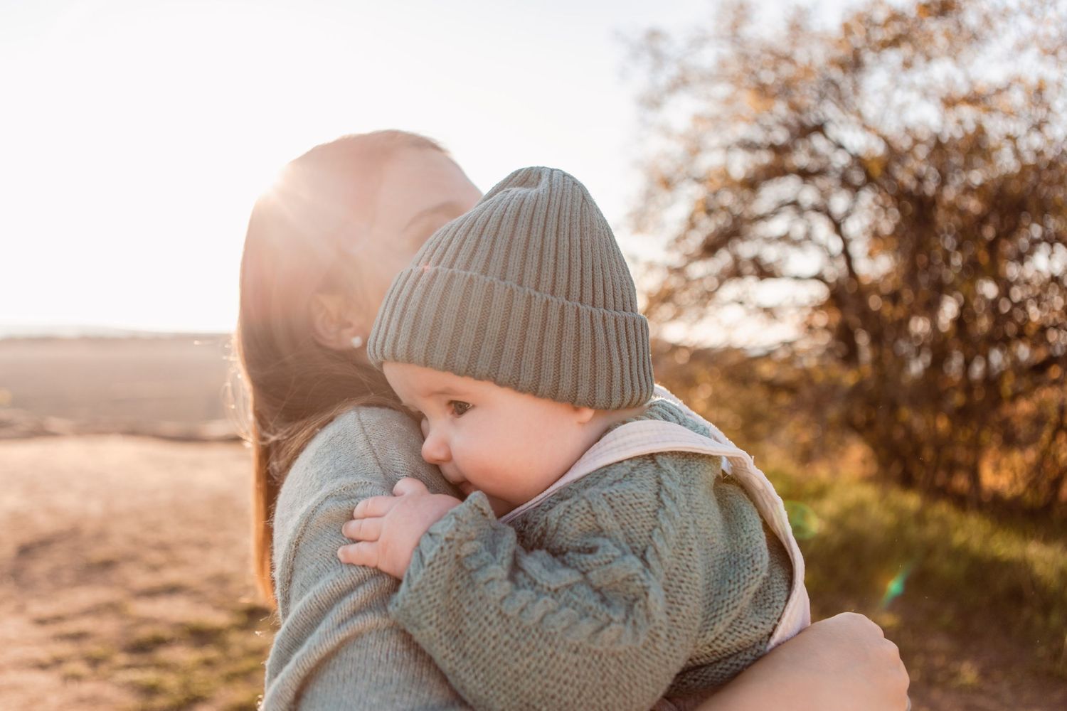 Cozy autumn family portrait with warm knit hats in natural outdoor setting.
