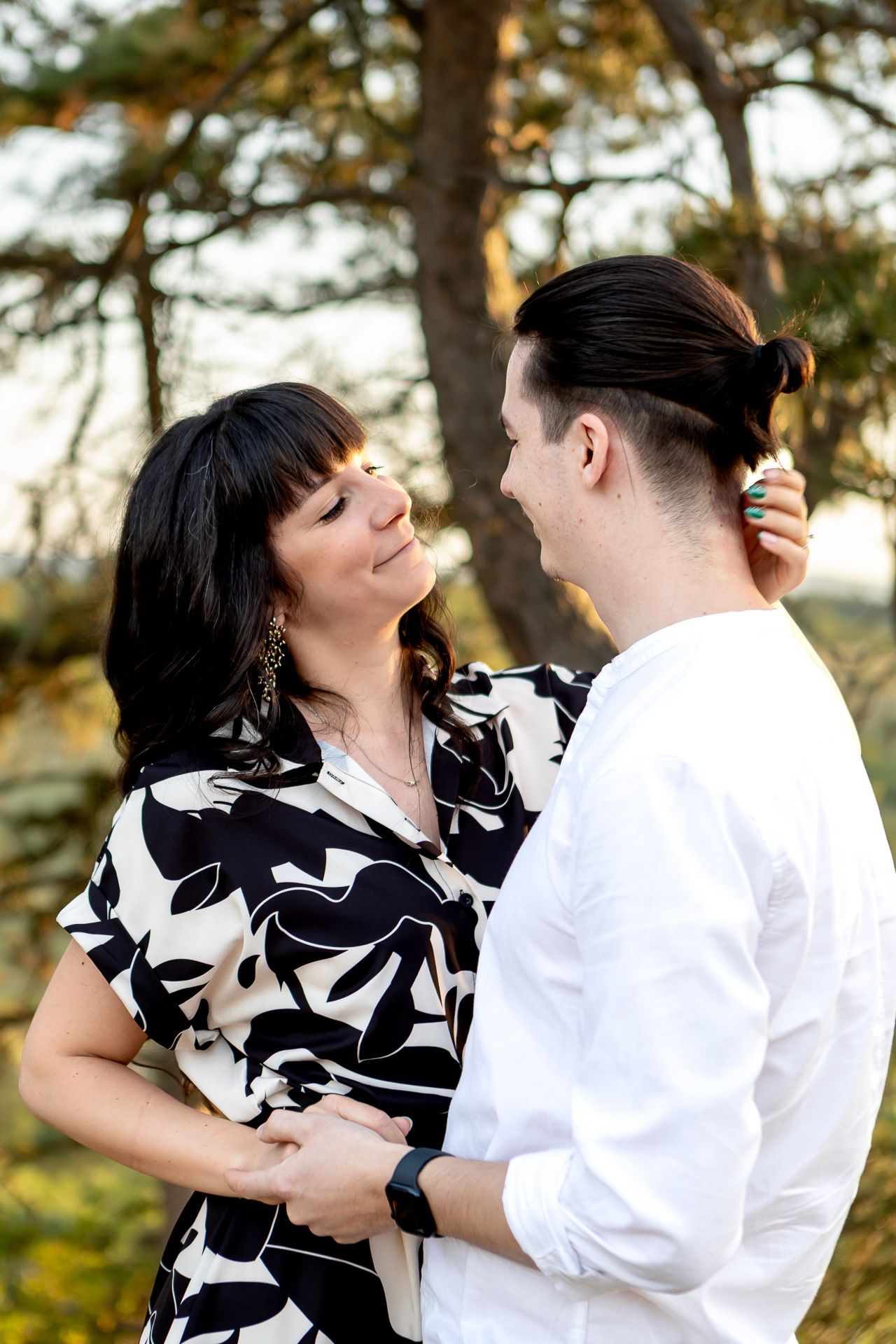 Couple in black and white dress sharing romantic moment outdoors.