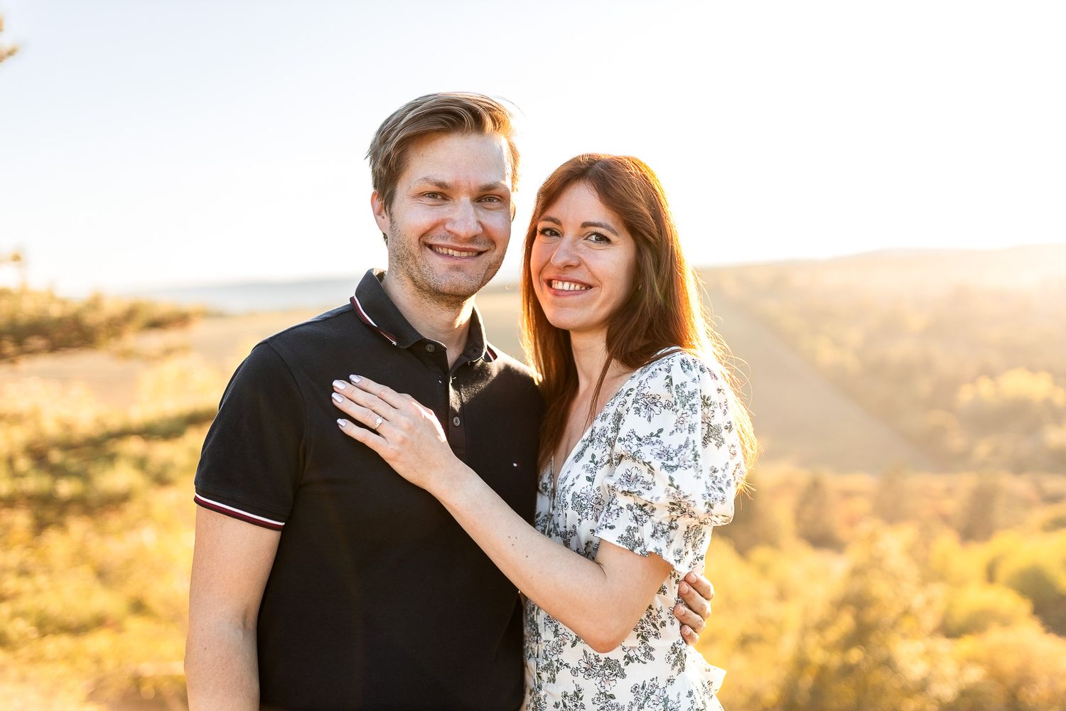 Romantic couple embracing during golden hour photoshoot in outdoor setting.