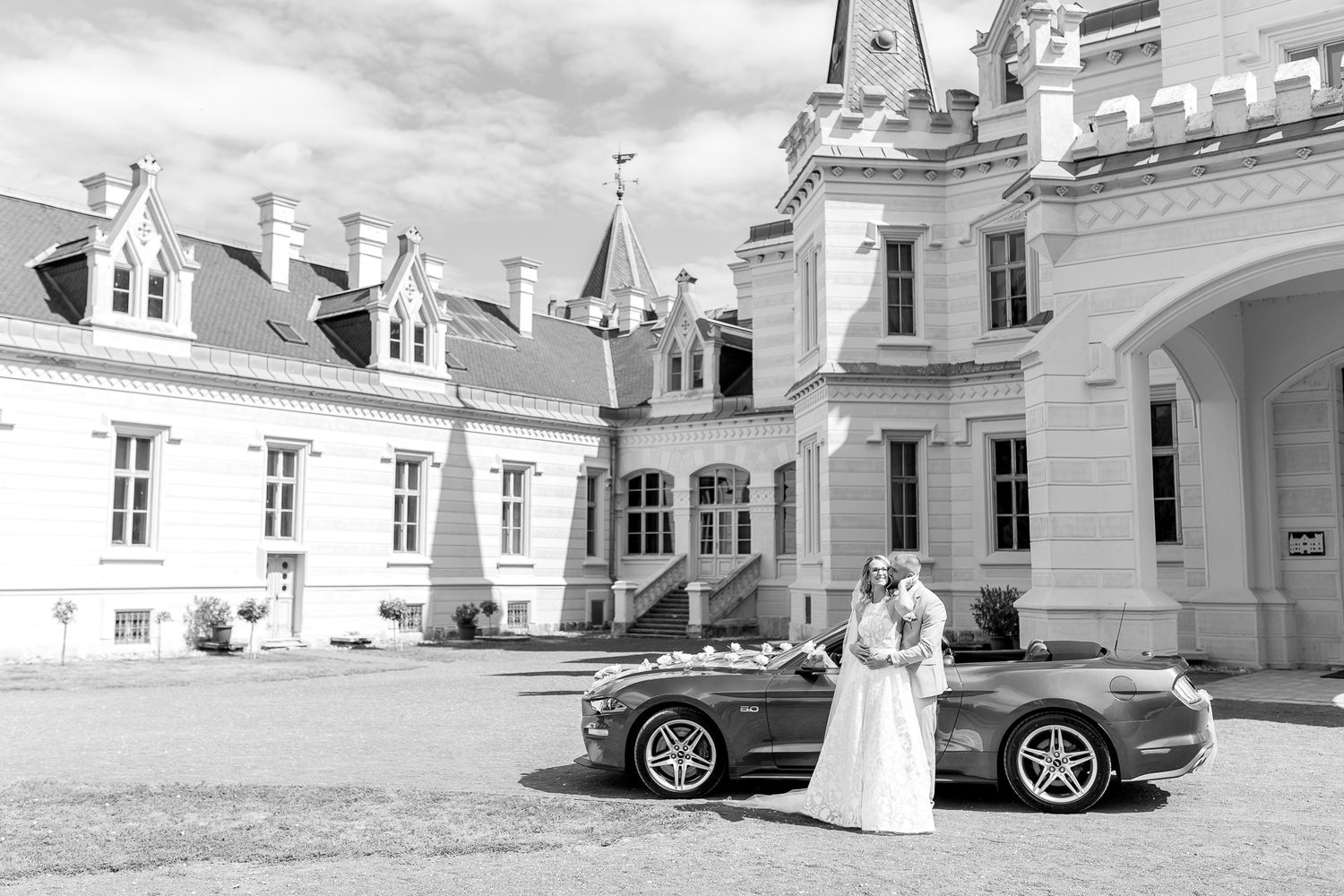 Vintage black and white photo of classic cars parked outside elegant white European-style buildings.