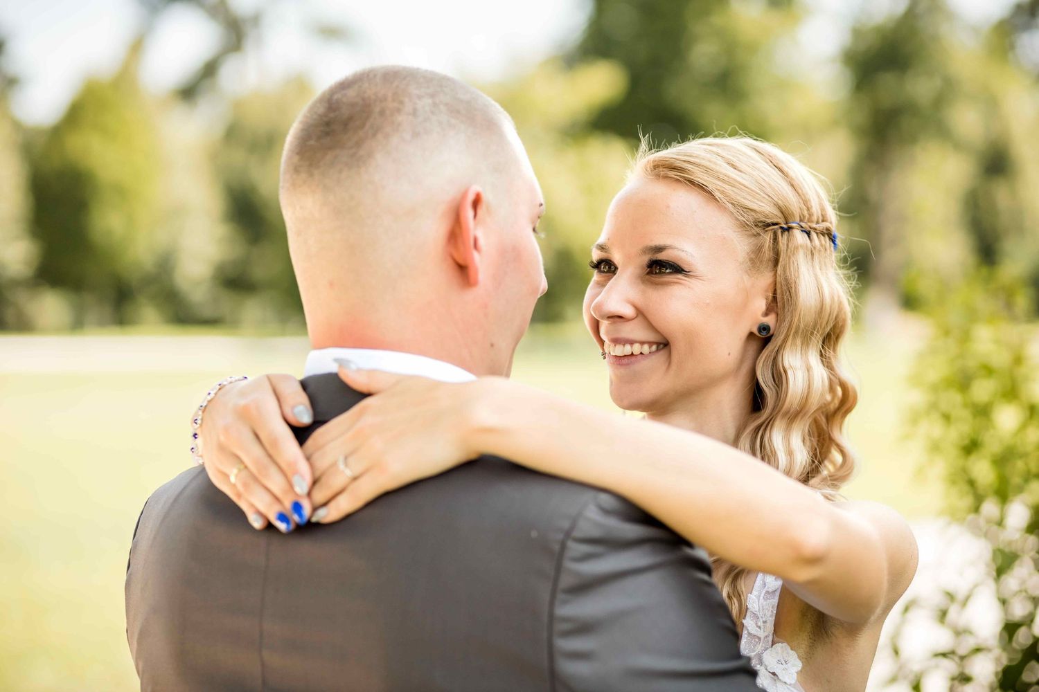 Romantic outdoor wedding embrace with bride in white dress and groom in grey suit.