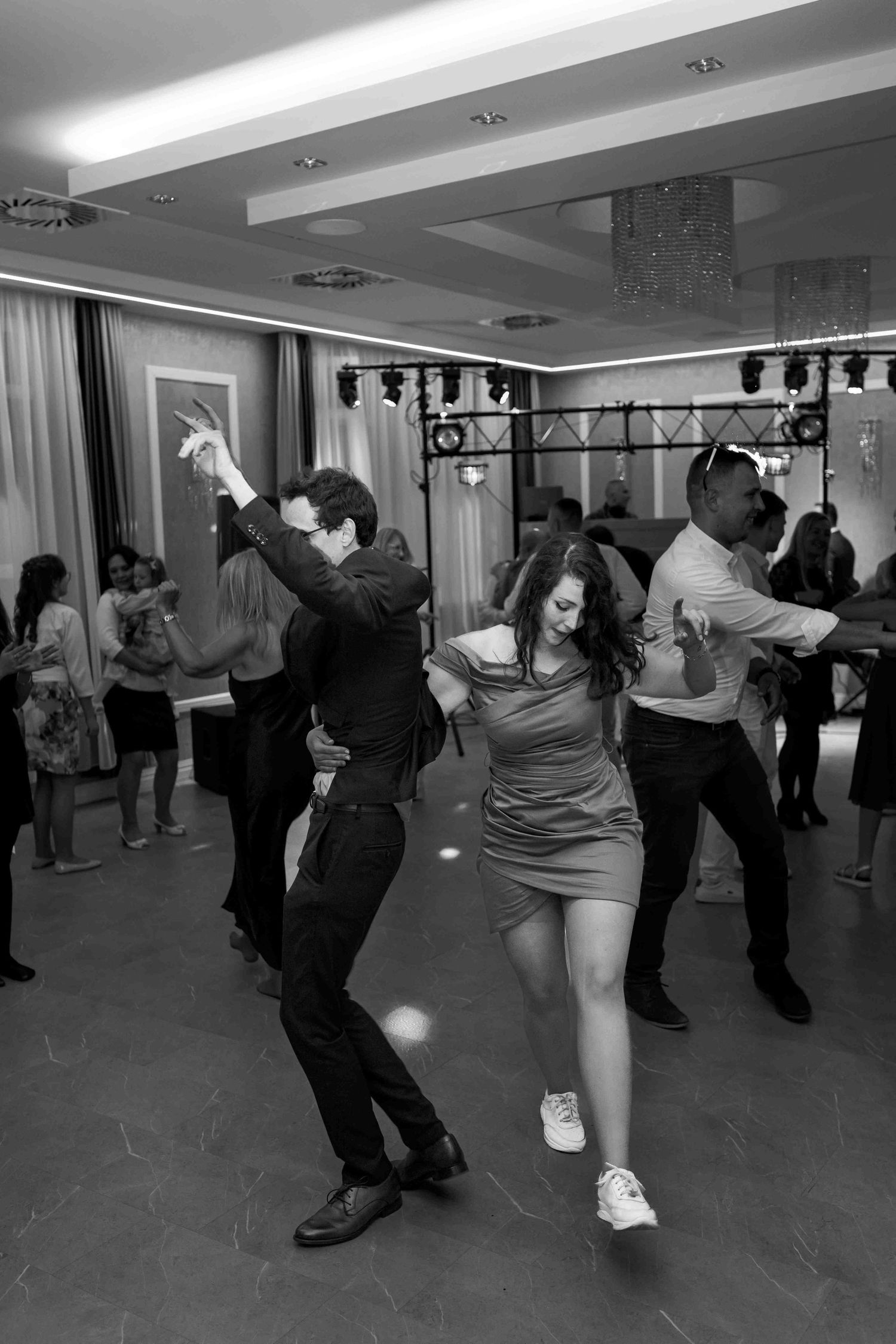 Dance partners practice their moves in a ballroom dance studio with dramatic lighting and shadows.
