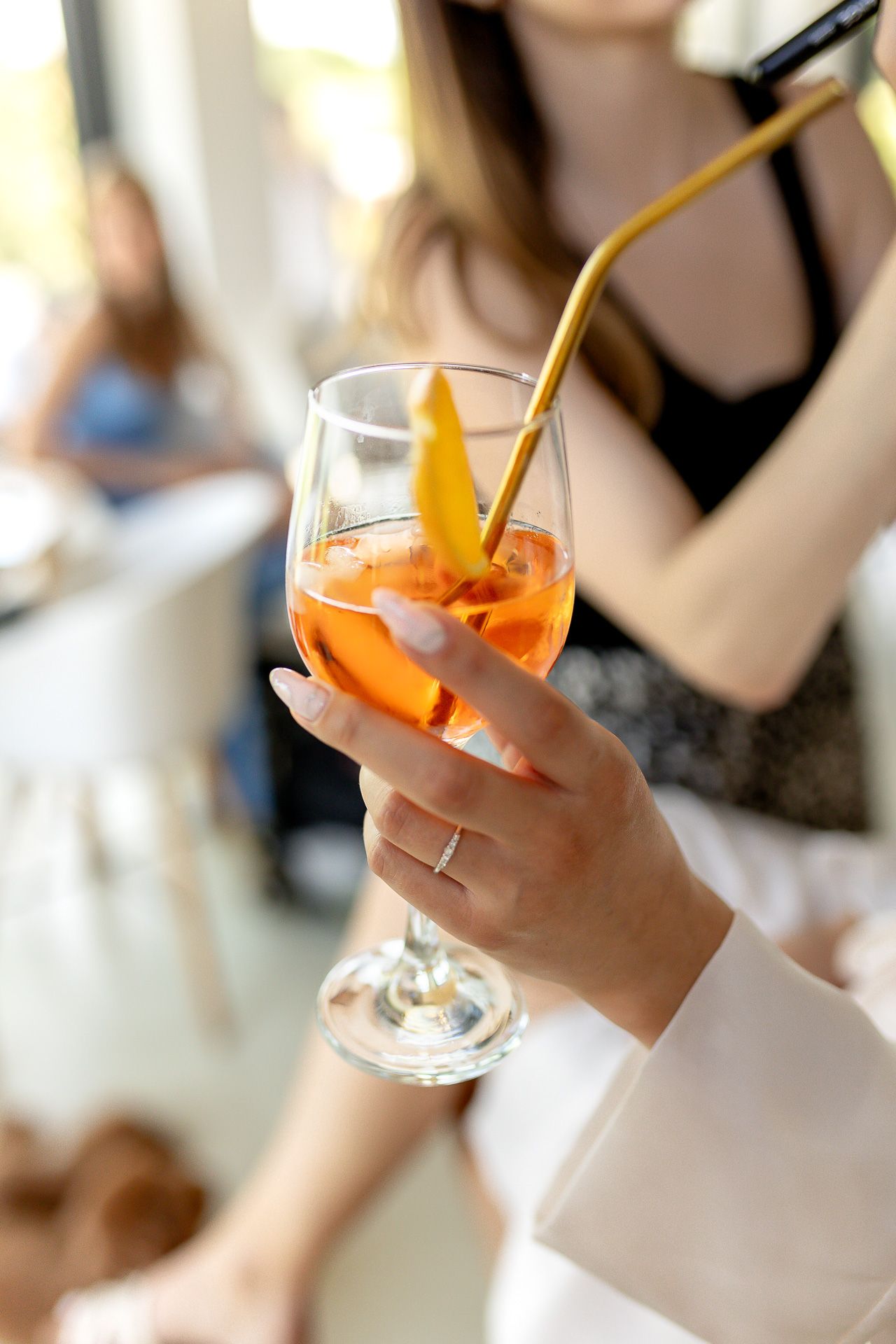 Hands holding orange cocktails garnished with citrus at an elegant event.