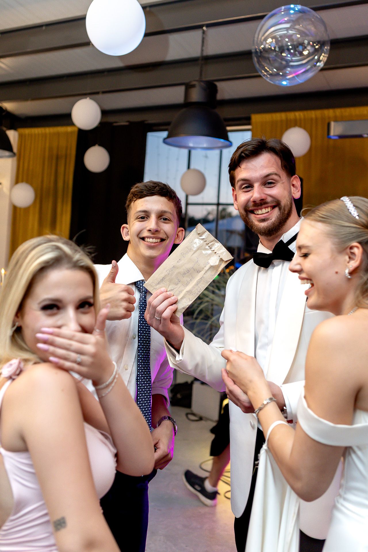 Wedding party celebrates with cash and laughter at indoor reception.