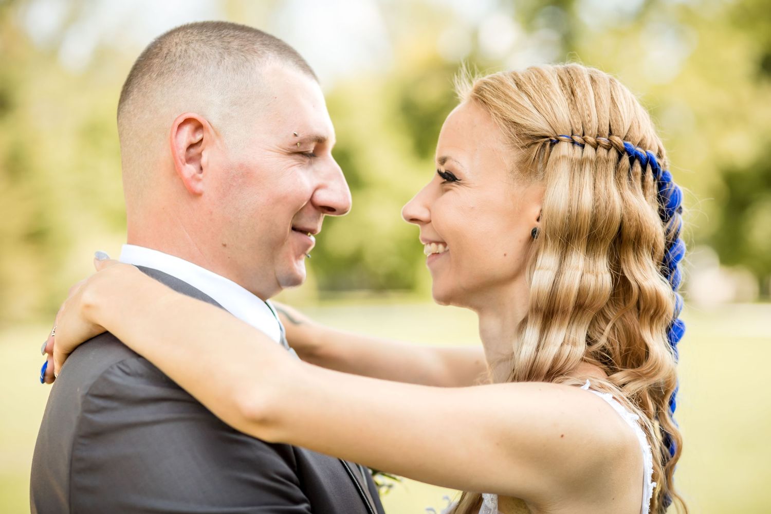 A couple shares a romantic moment together in a sunny outdoor setting with natural bokeh background.