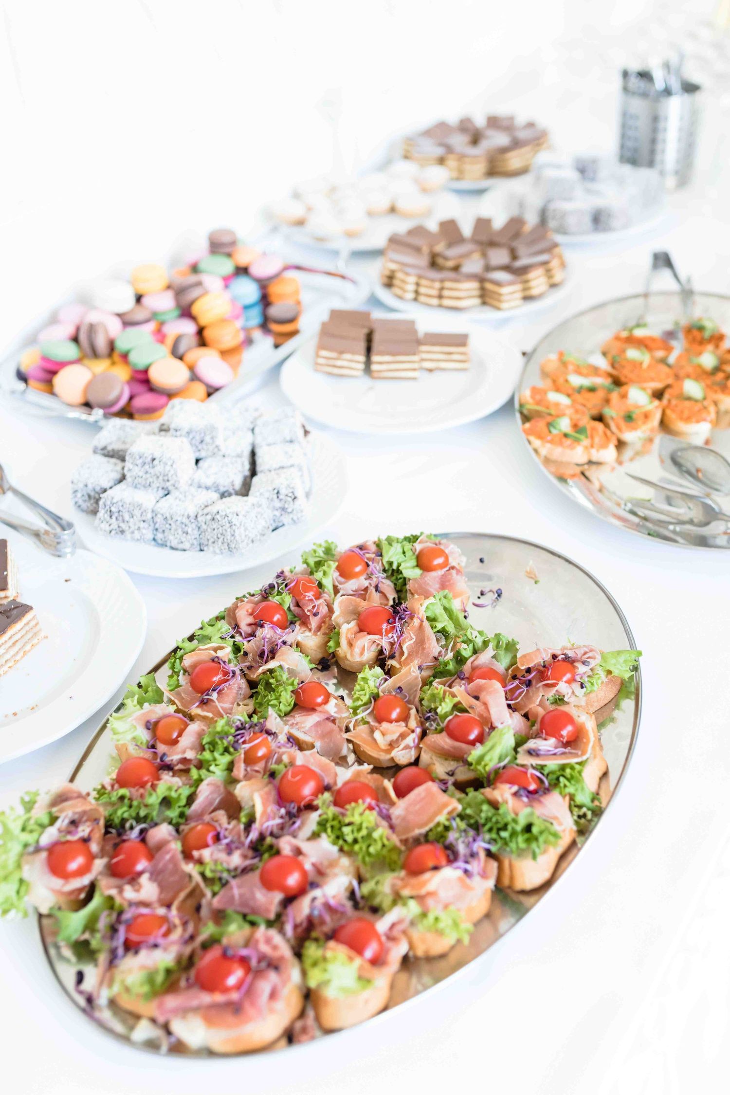 Elegant catering display of appetizer platters with assorted canapes and finger foods arranged on white serving dishes.