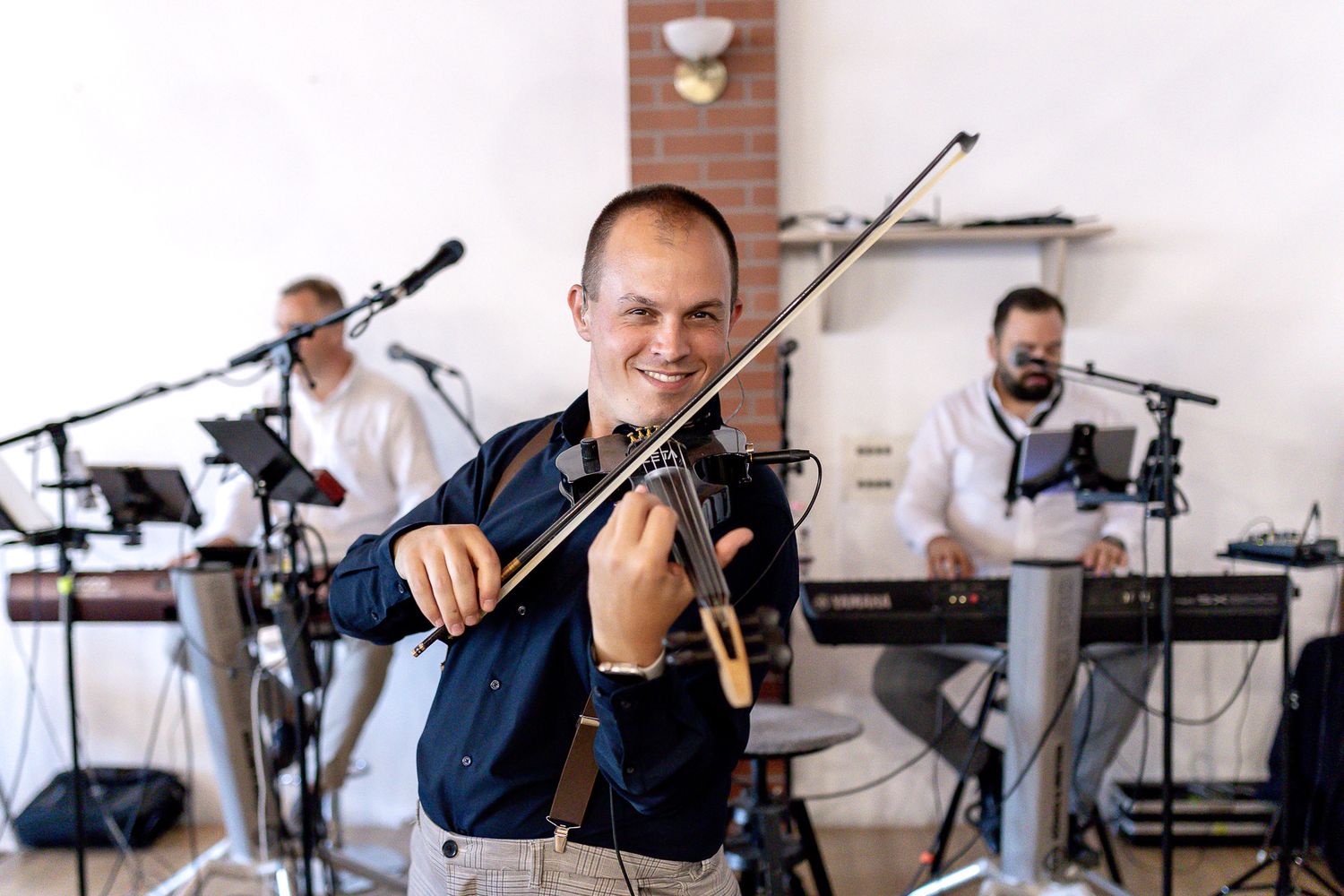 Musicians performing with violins and other instruments on stage during a live performance.