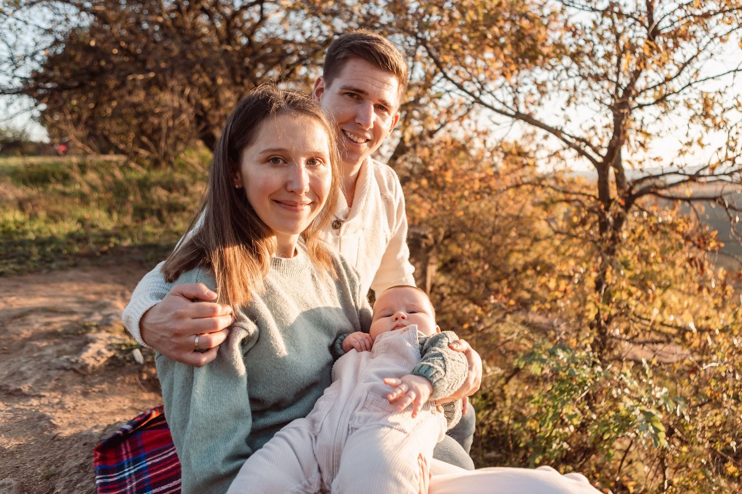 Outdoor family portraits set against a backdrop of golden autumn foliage at sunset.