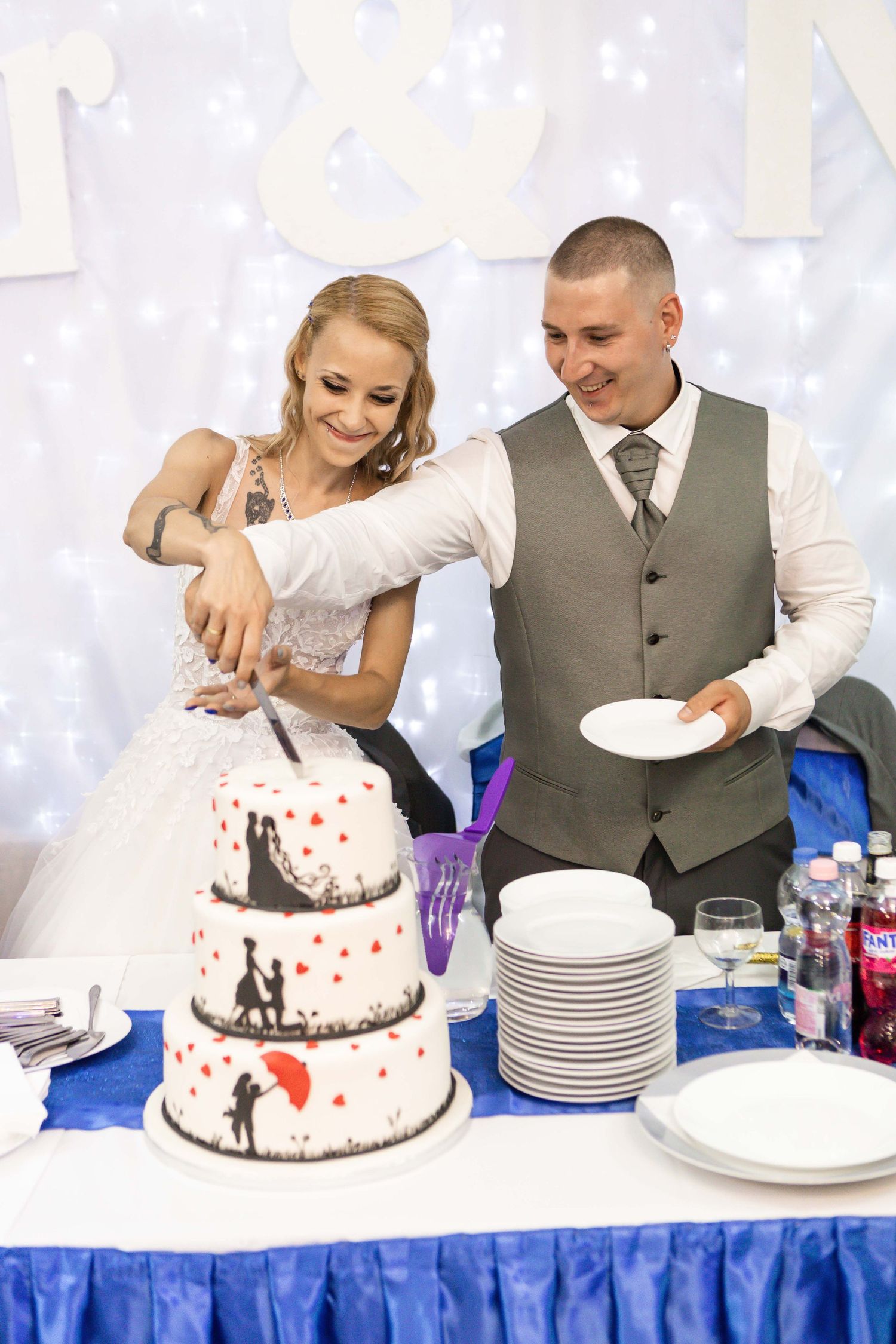 Wedding couple cuts into their black and white wedding cake decorated with red hearts at their reception celebration.