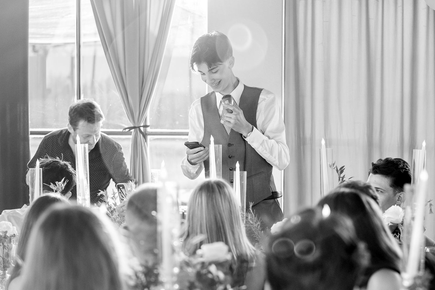 Black and white photo capturing emotional reactions during wedding speeches.