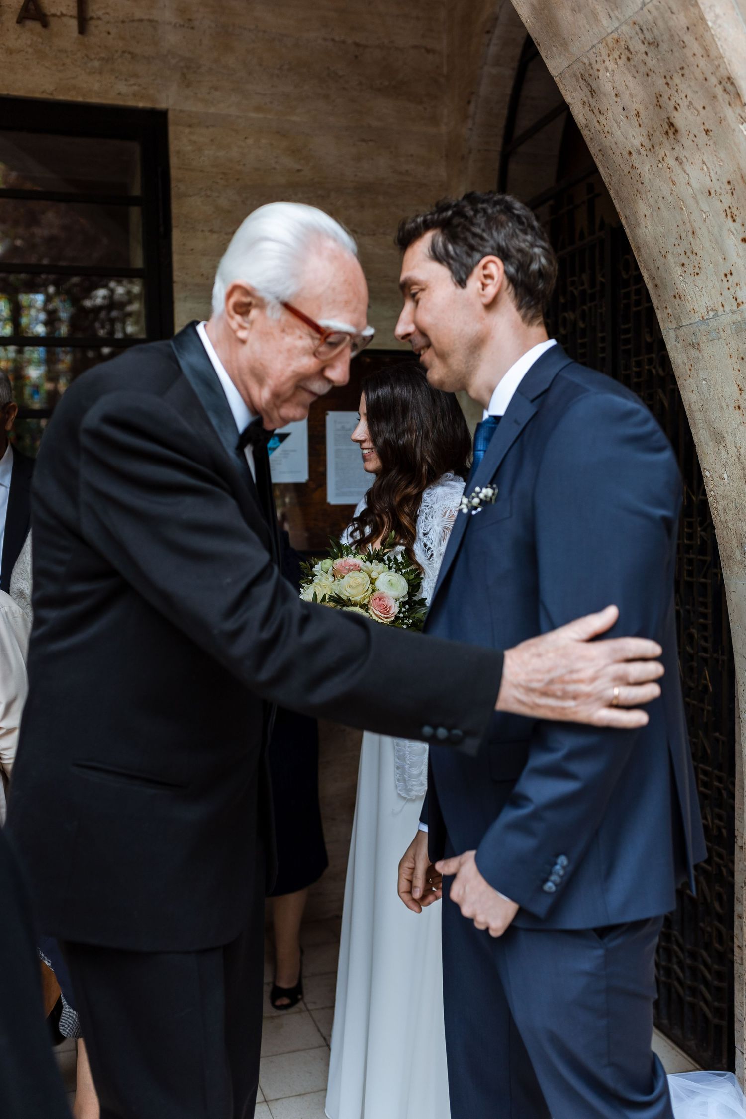 A sequence of four photos showing an emotional embrace between two people at a formal event.