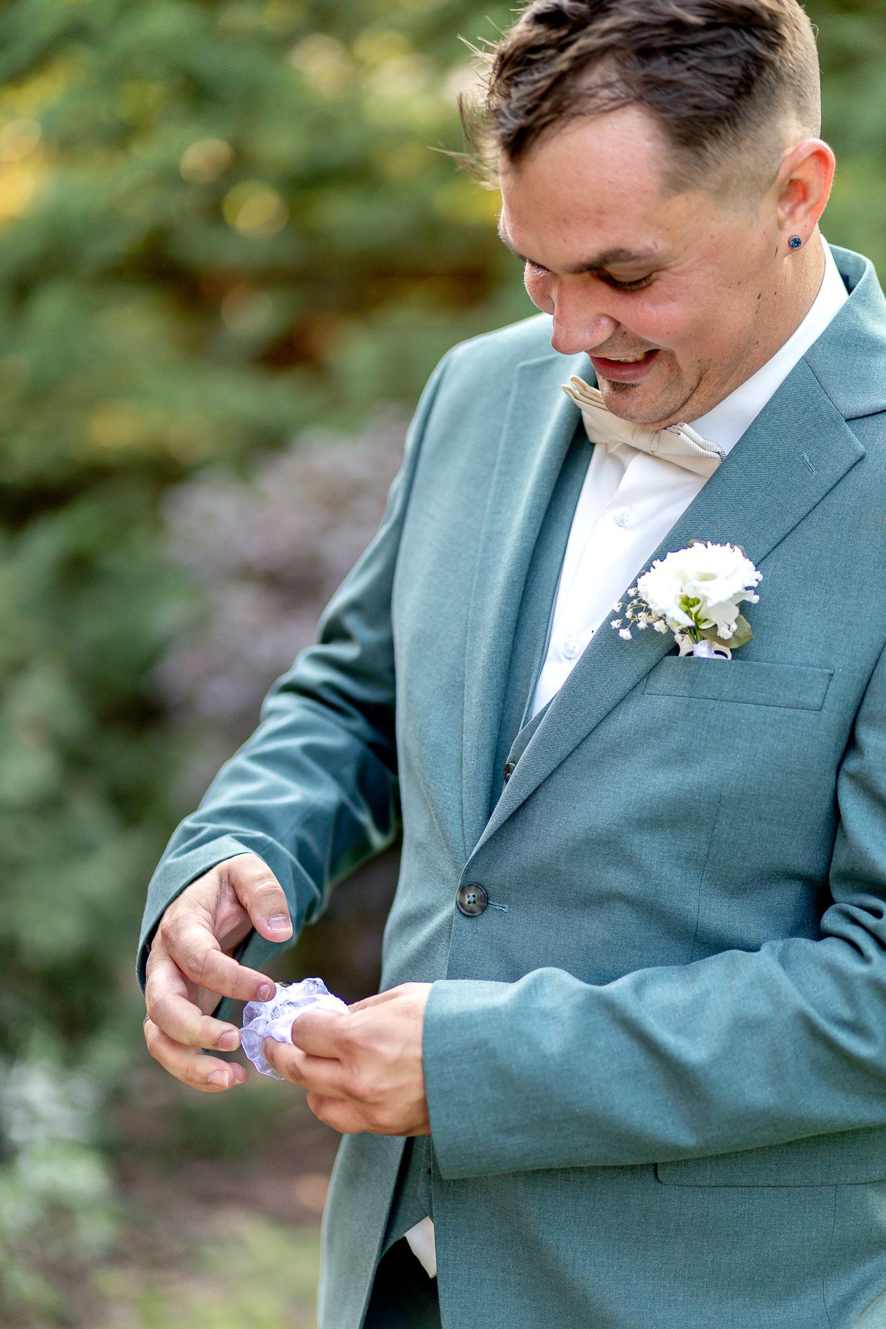 A person in a light blue suit jacket smiles while looking down at something in their hands.