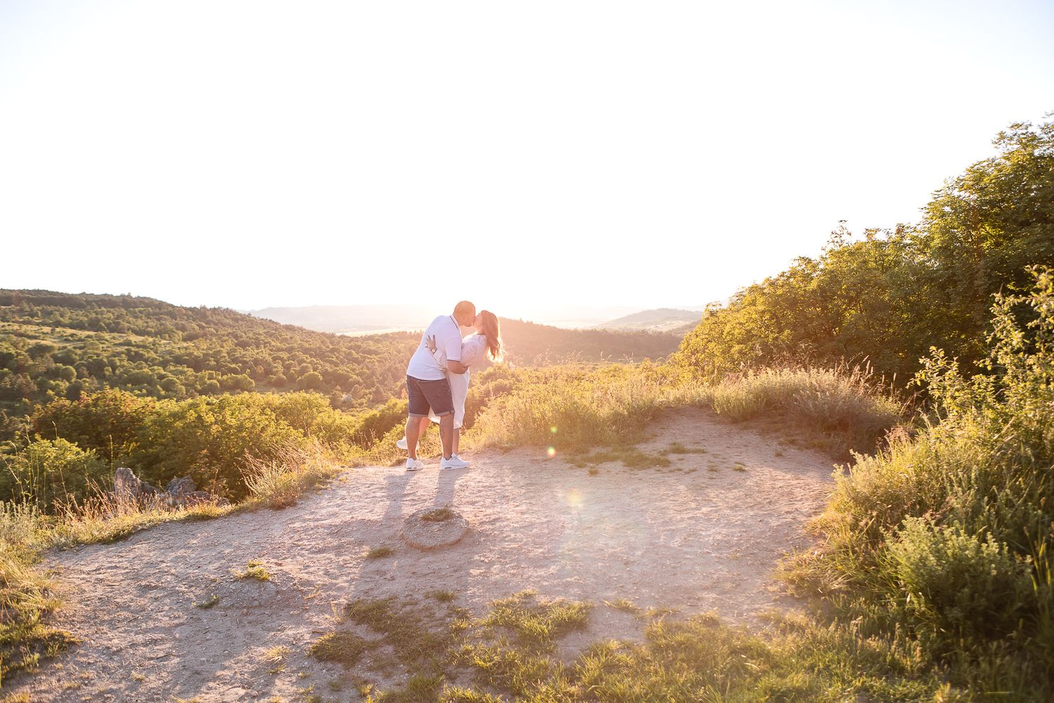 Distant view of couple walking mountain trail during sunset.