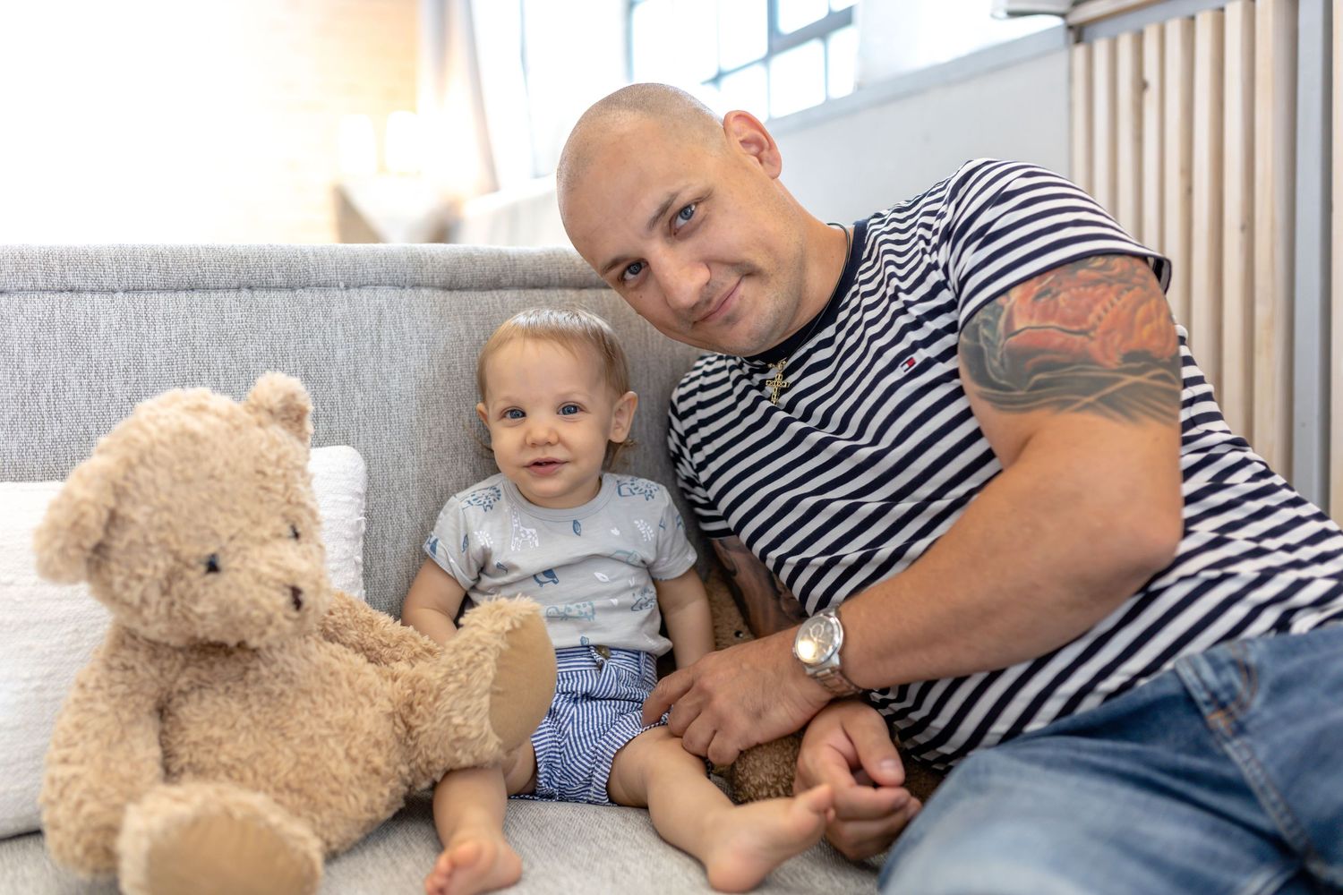 Casual indoor family moments with a teddy bear and striped shirt against white walls.