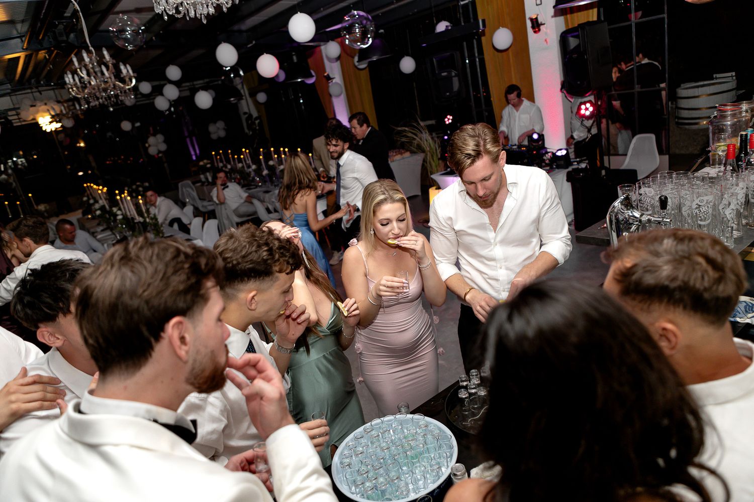 Lively crowd dancing and celebrating at a dimly lit party venue.