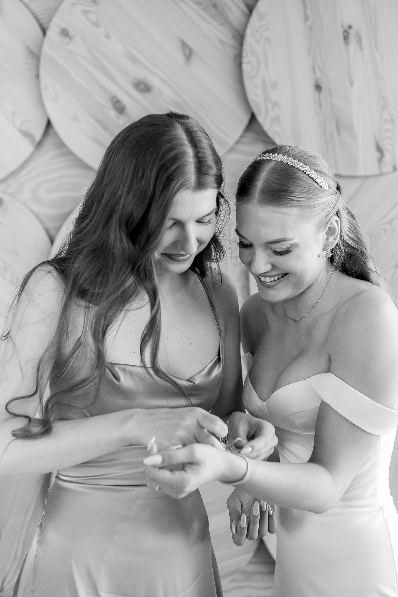Two people share a joyful moment while looking at something together in a bridal setting.