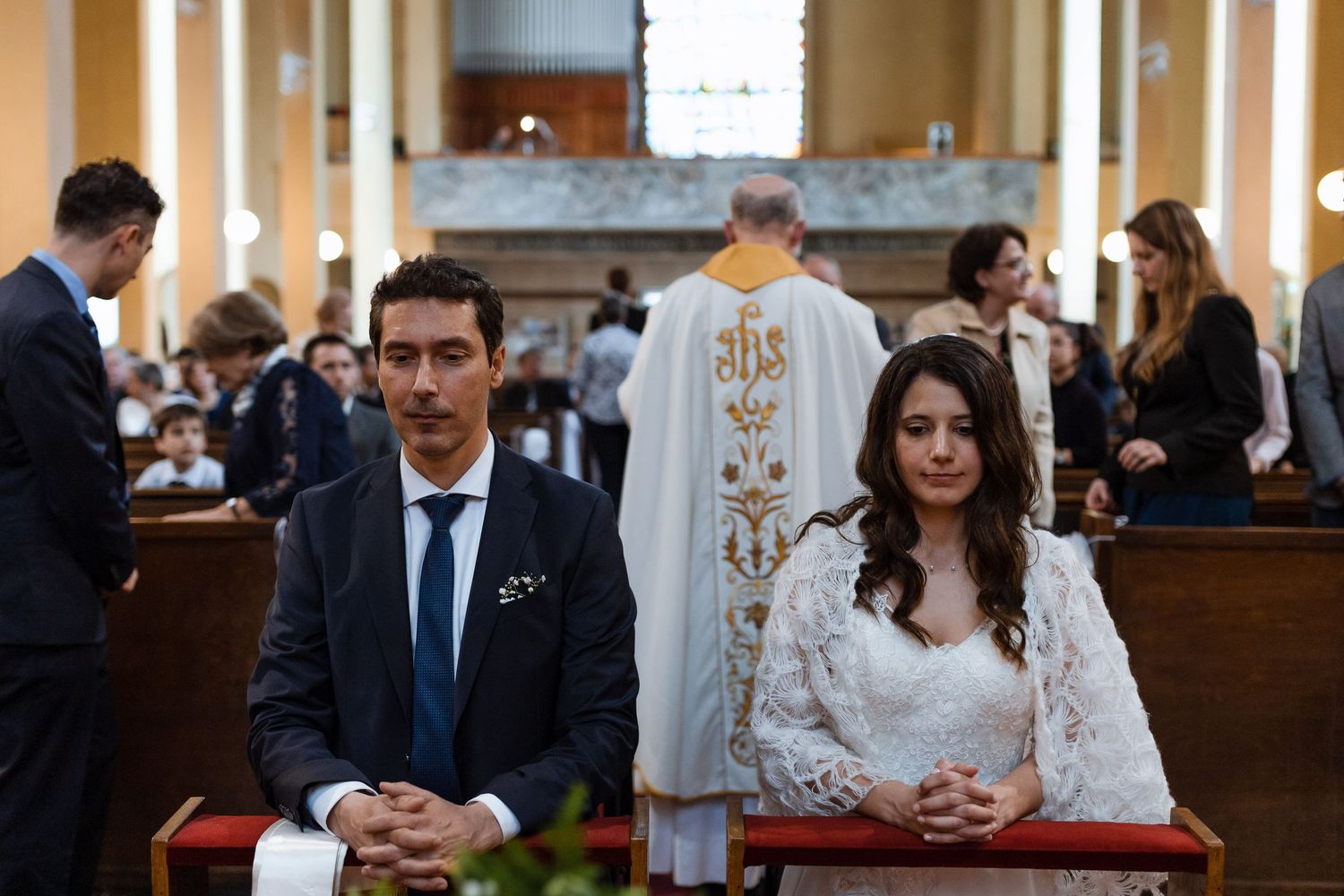 A couple shares a tender moment during their wedding ceremony in an ornate church with decorative details.