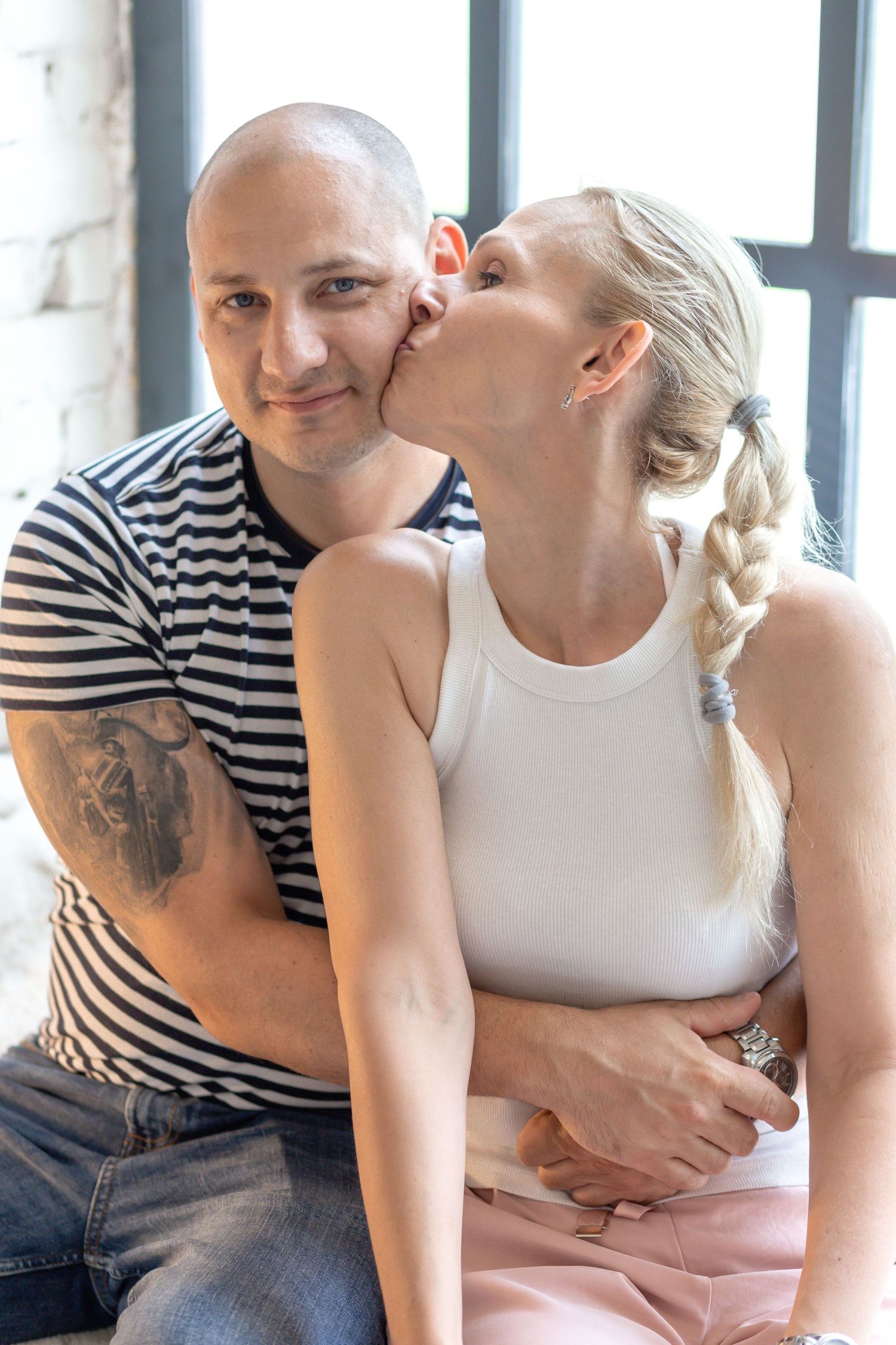 Intimate family portrait with striped shirt and white tank top against window light.