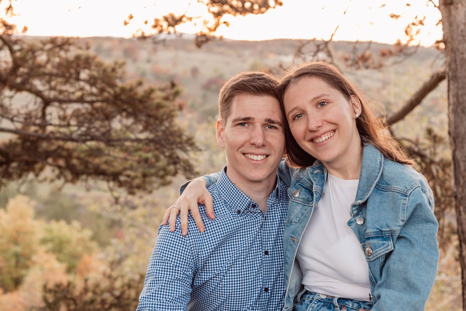 Couple in coordinating denim and blue outfits posing outdoors during sunset.
