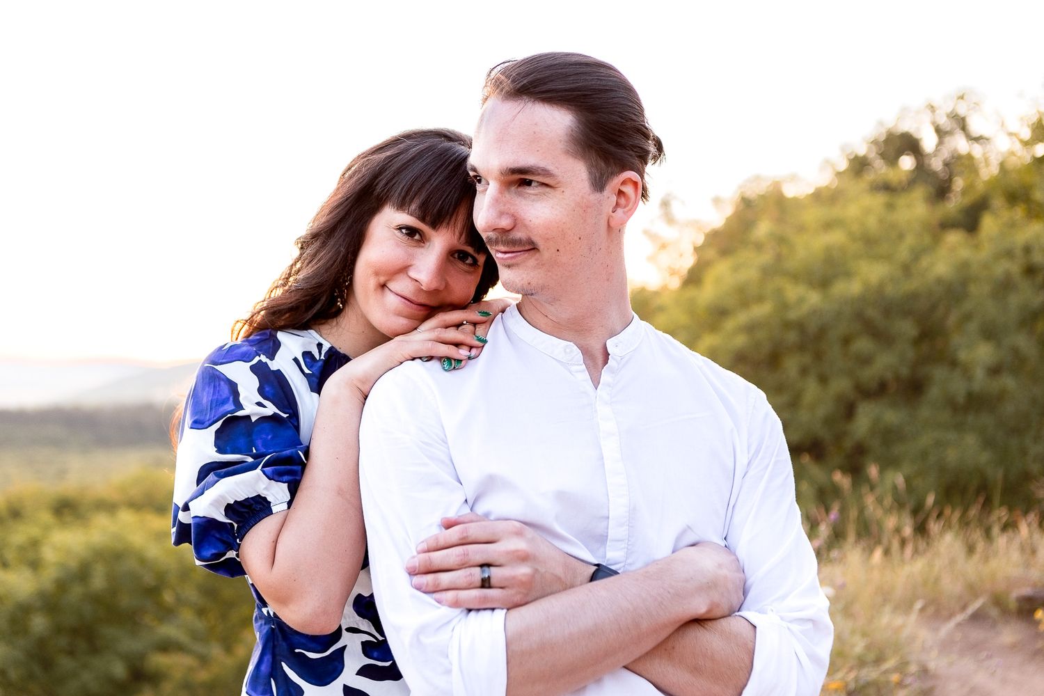 A couple shares joyful laughter during an outdoor portrait session at sunset.