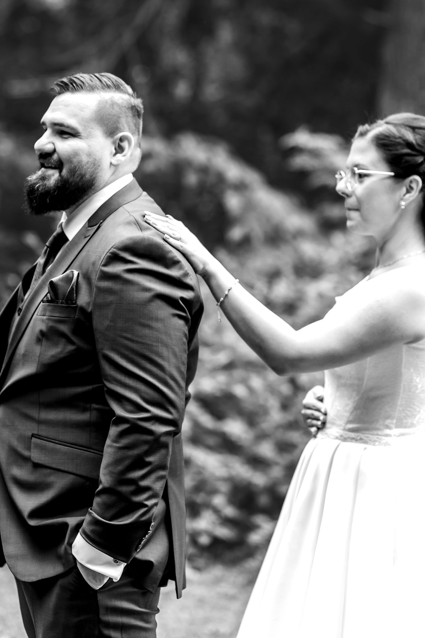Black and white wedding photo showing couple sharing a romantic kiss during their outdoor ceremony.