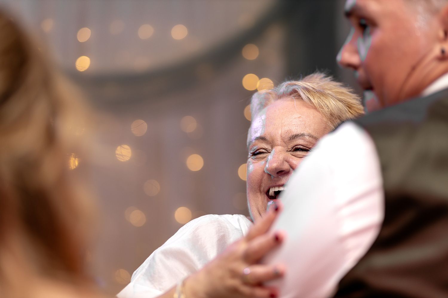 A wedding ceremony scene with soft bokeh lights and decorative elements in the background.