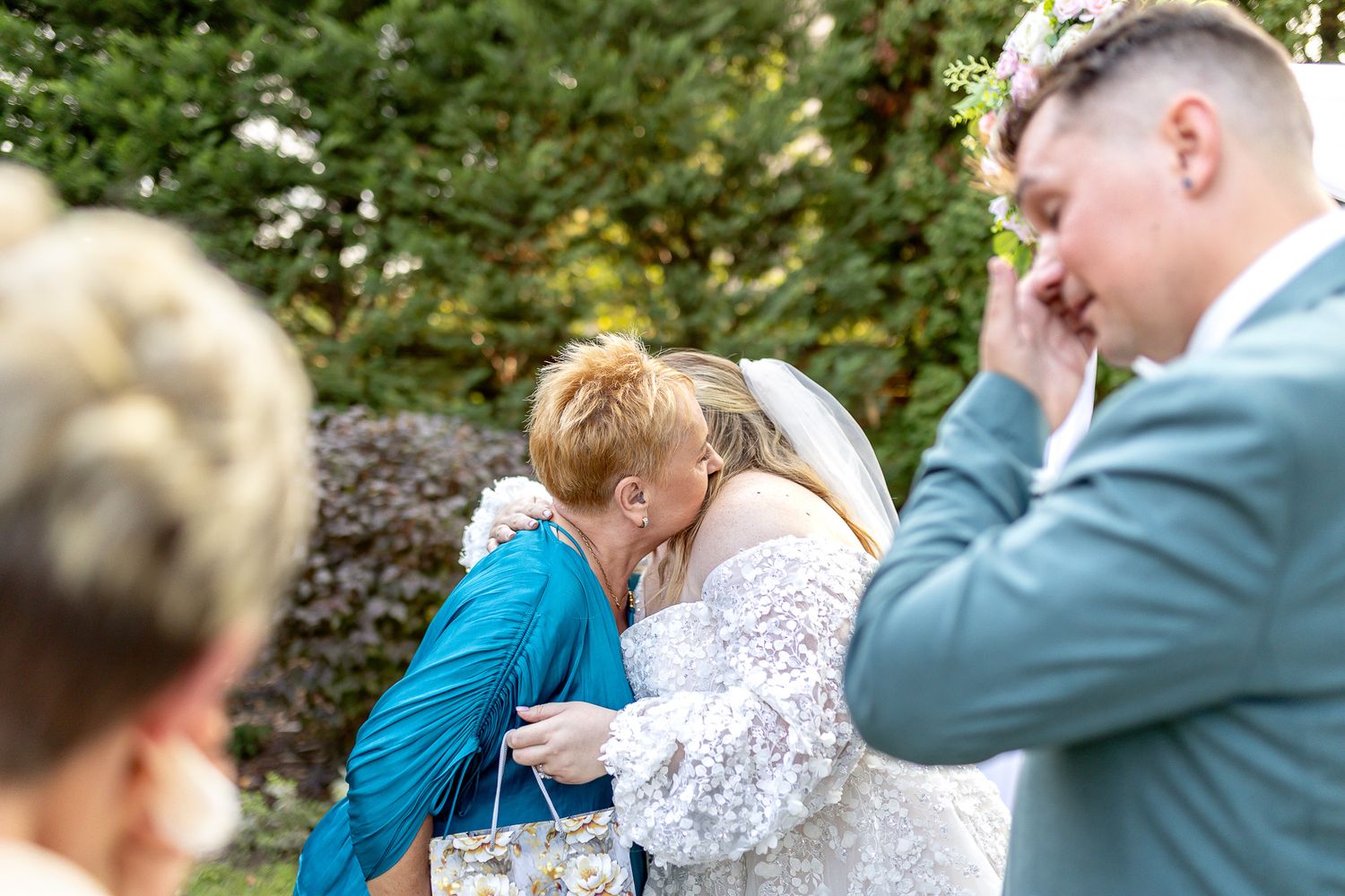 Wedding party members in blue and gray suits share joyful moments during an outdoor celebration.