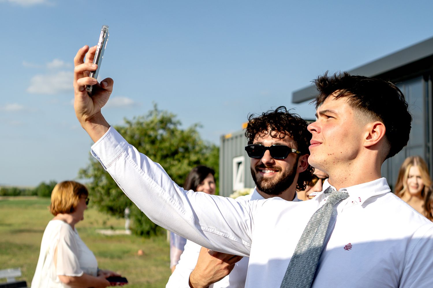 Groomsmen celebrating and toasting outdoors in white shirts.