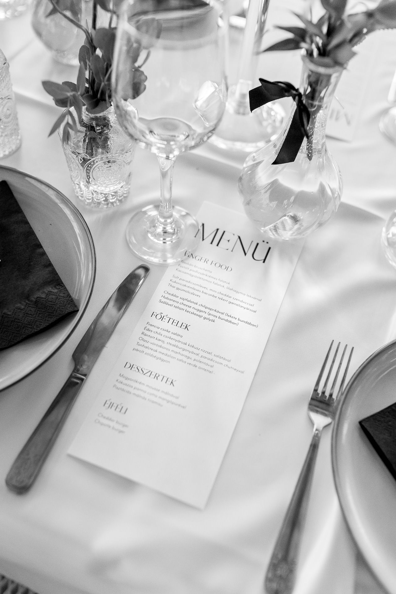 Formal place setting with menu card, silverware, and white plates on crisp linens.