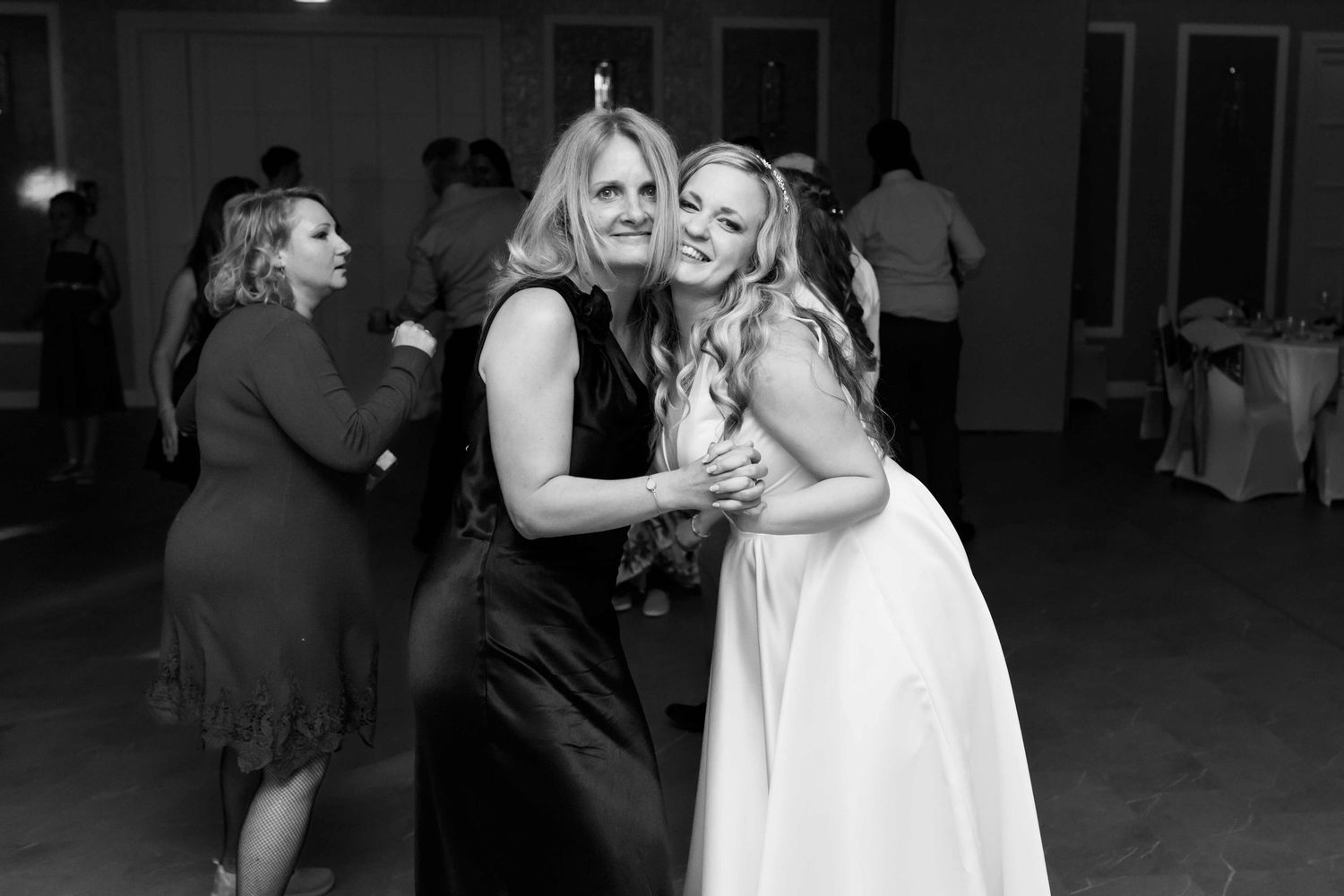 Two people dancing and embracing on a dance floor at a formal event in black and white photography.