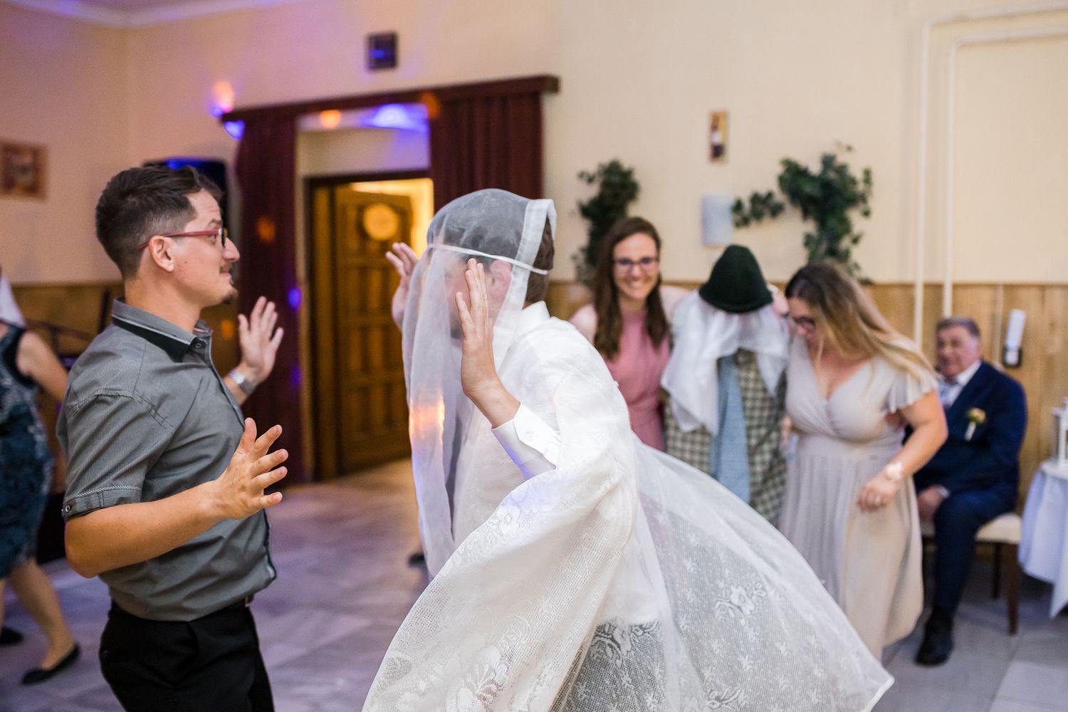 Wedding guests dance and celebrate together on the dance floor at an indoor reception venue.