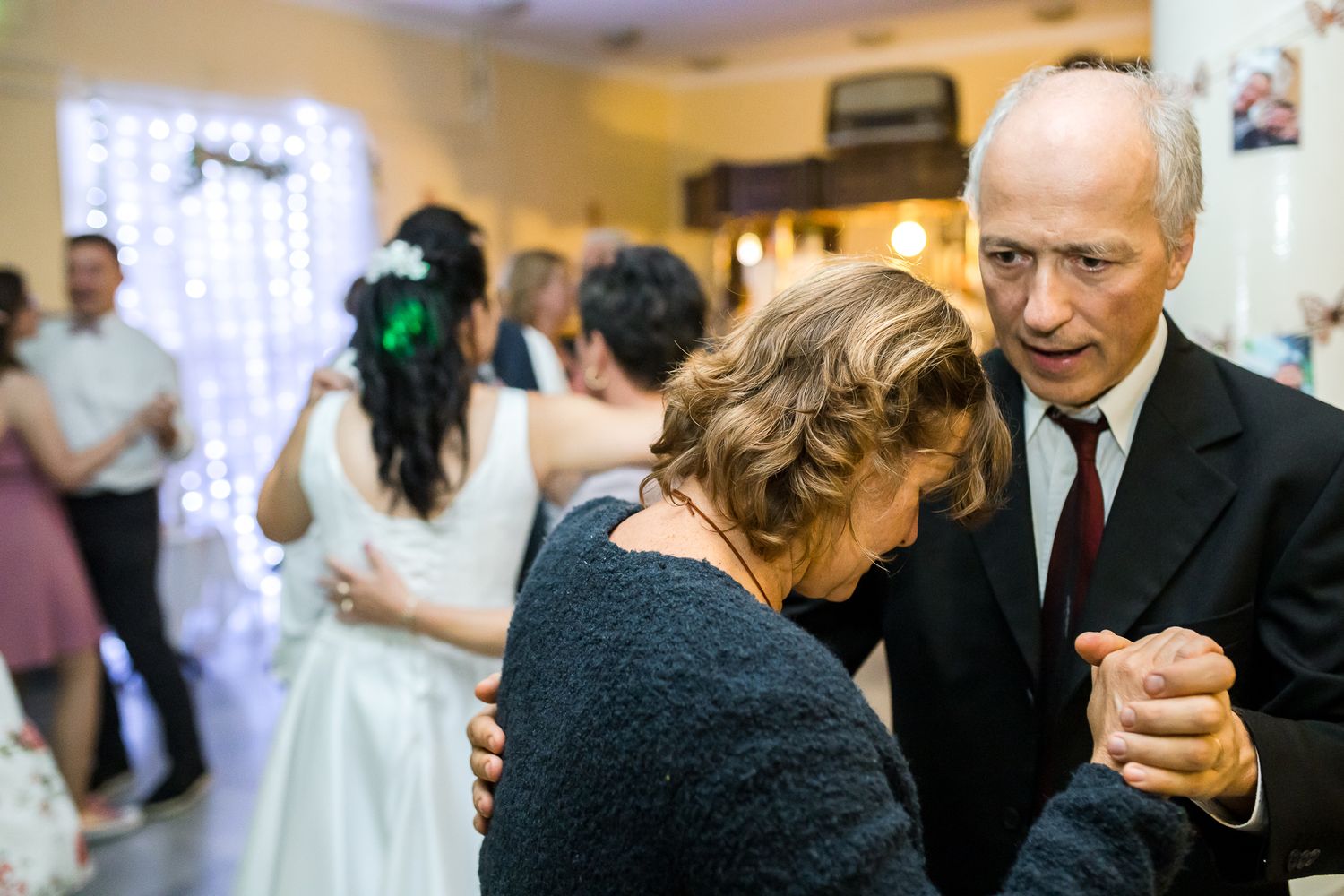 Wedding guests dance together on a reception dance floor under warm lighting.