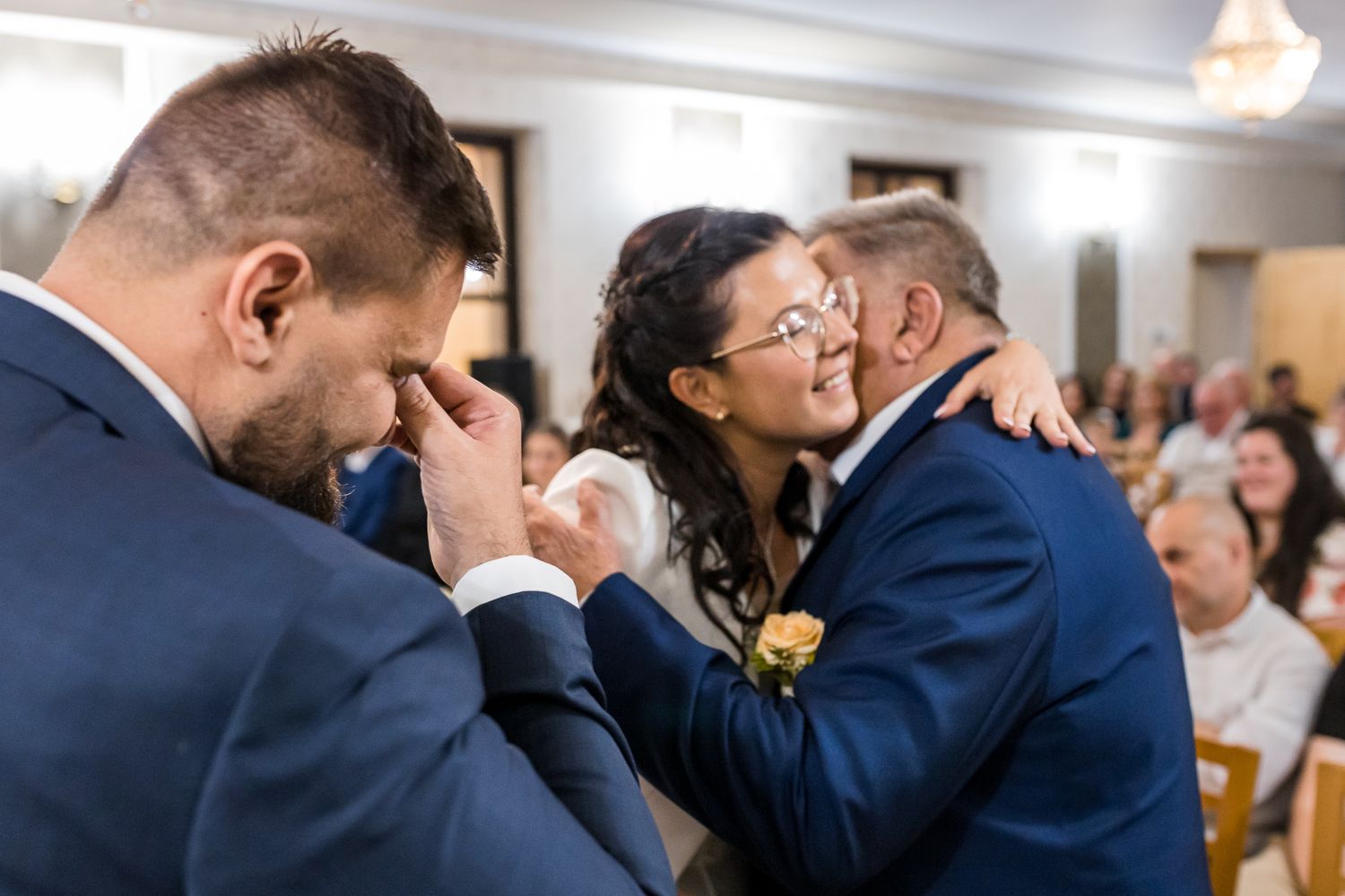Wedding guests celebrate and dance together during a joyful reception celebration in an indoor venue.