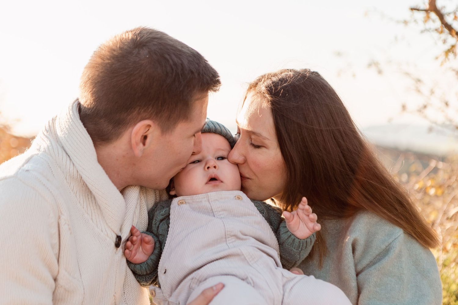 Intimate family portrait session during sunset in a natural outdoor setting.