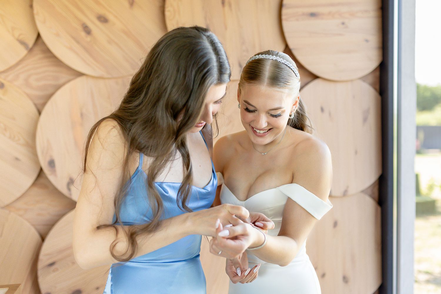 Two people share a happy moment while looking at something together against a wooden wall.