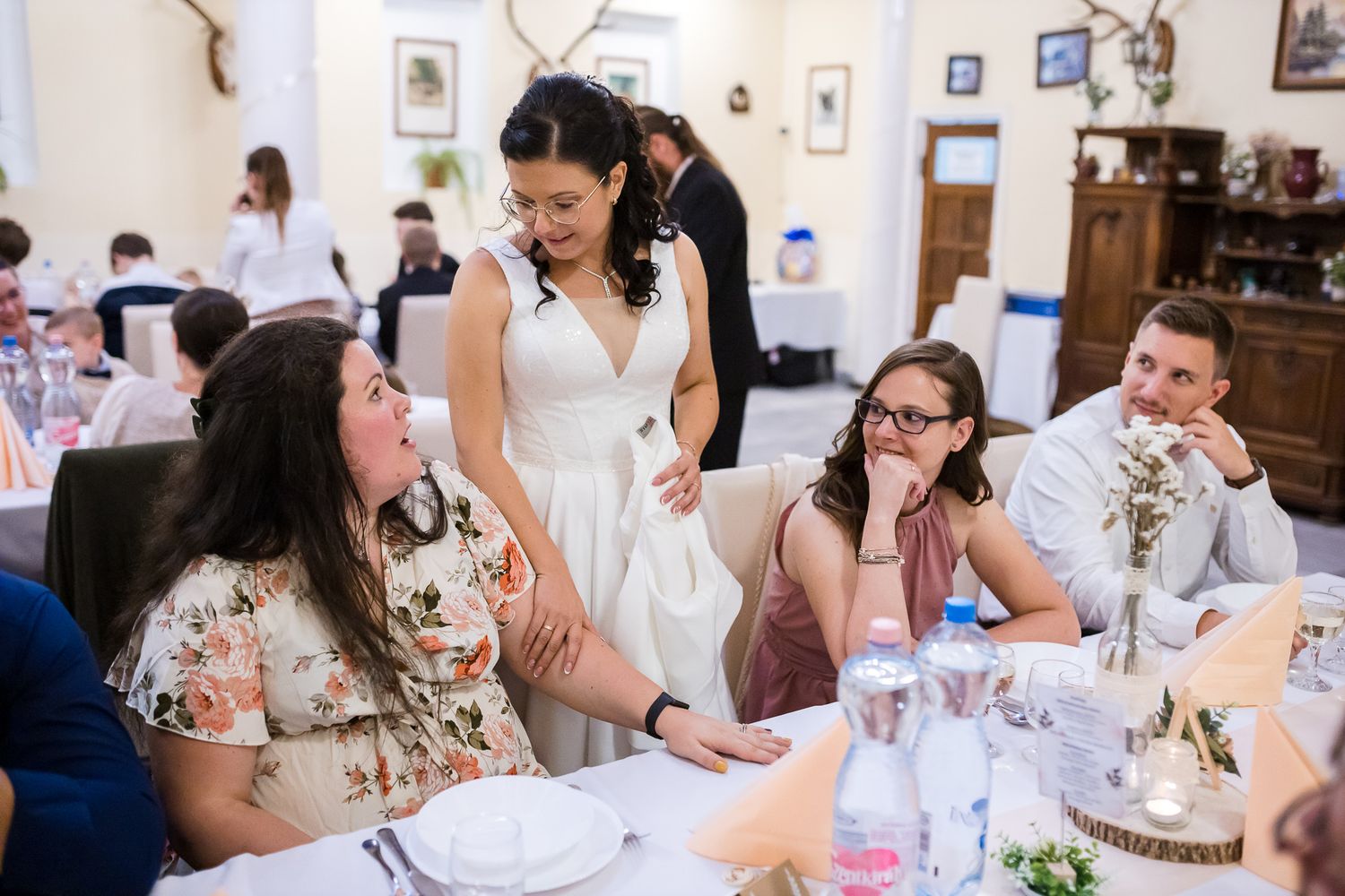 Wedding guests enjoy conversation and refreshments at elegant tables decorated with floral centerpieces during a reception.