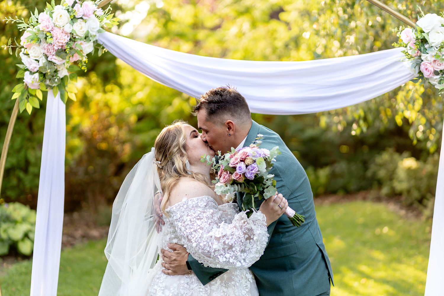 Romantic outdoor wedding ceremony under white fabric draping with autumn foliage in background.