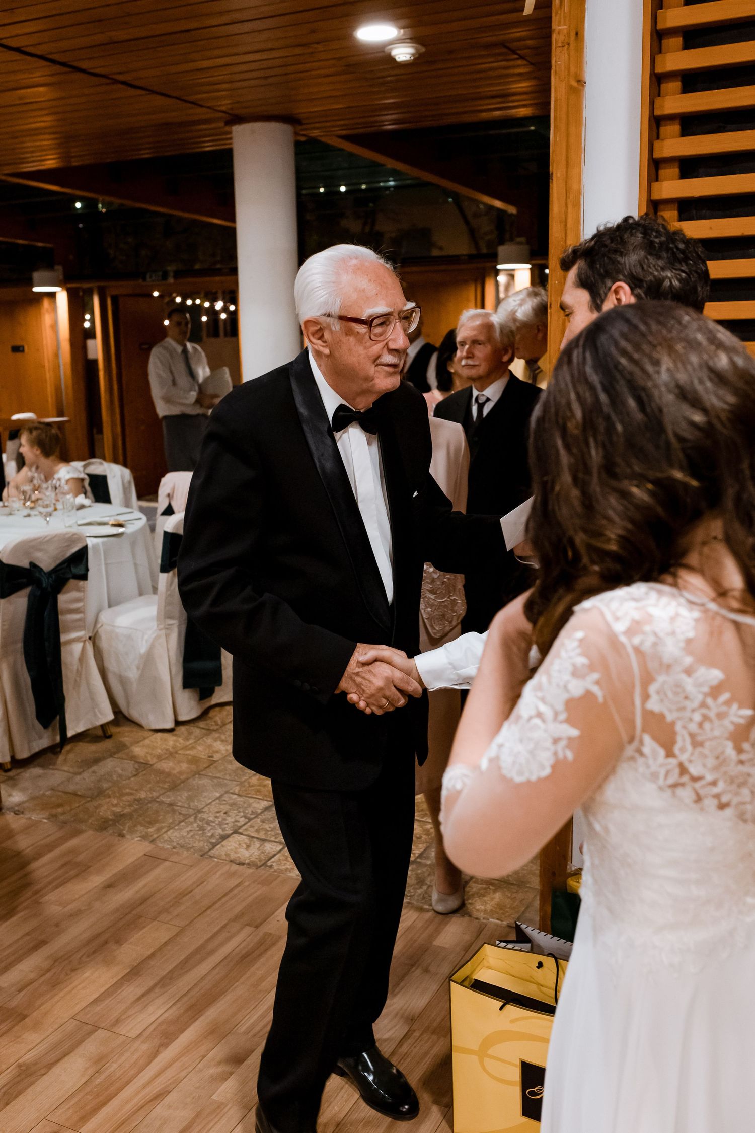 A couple shares a romantic dance together at a wedding reception on a wooden dance floor with white decor.