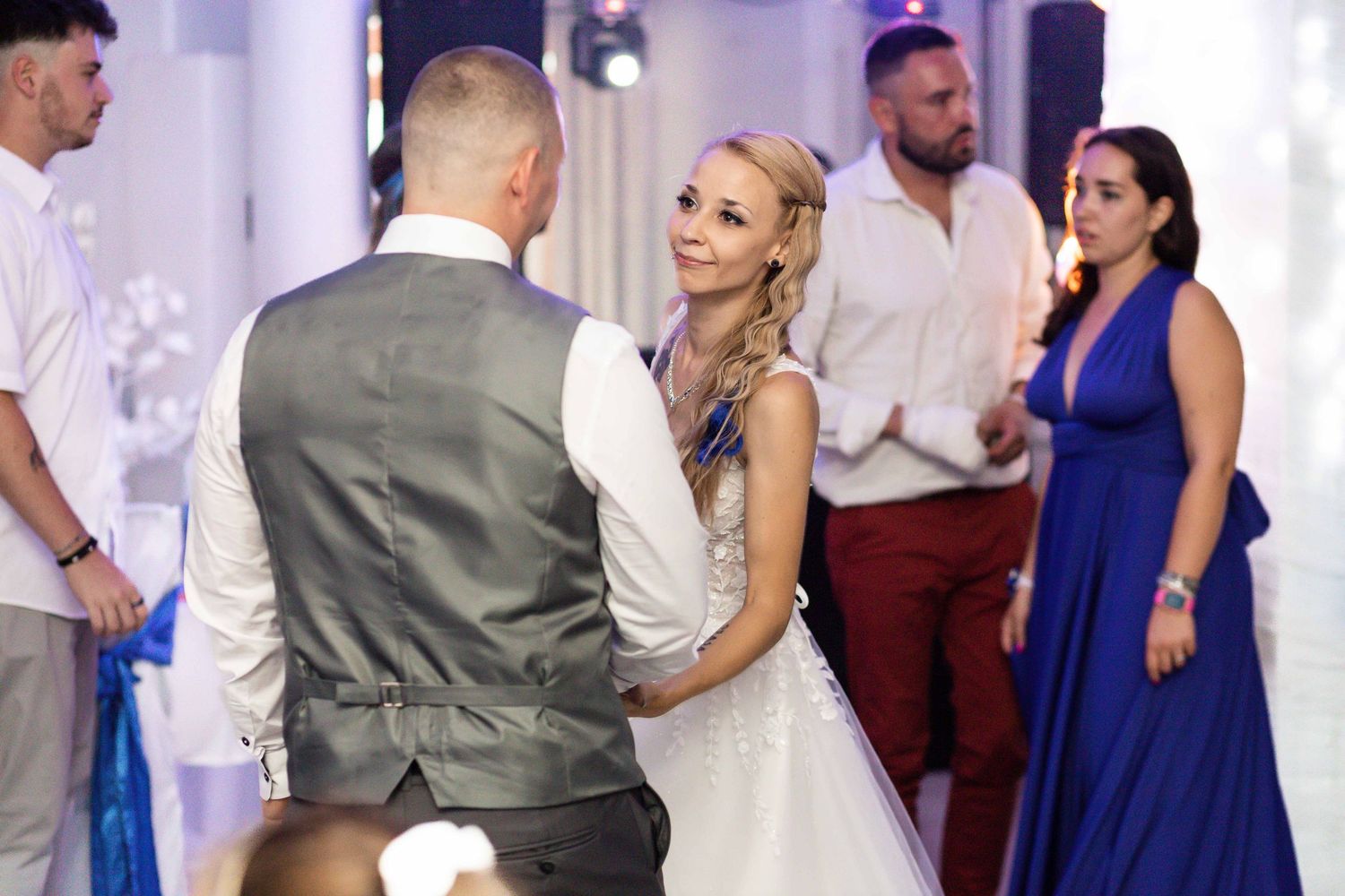 Wedding guests dance and celebrate on a purple-lit dance floor at an elegant reception venue.