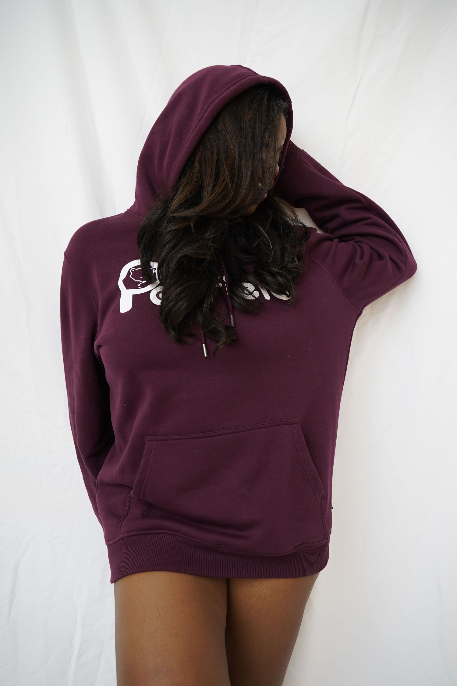 Fashion shot of maroon oversized hoodie against white backdrop.