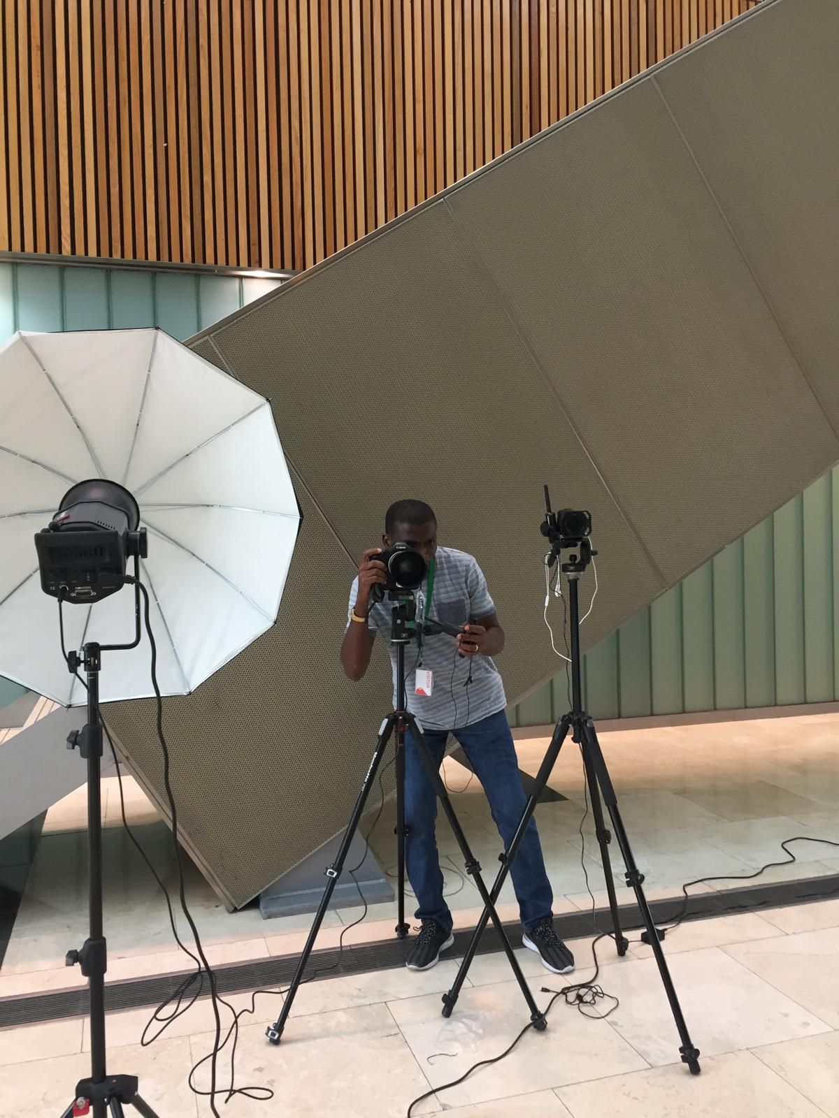 Professional photography setup with lighting equipment and reflectors in studio space.