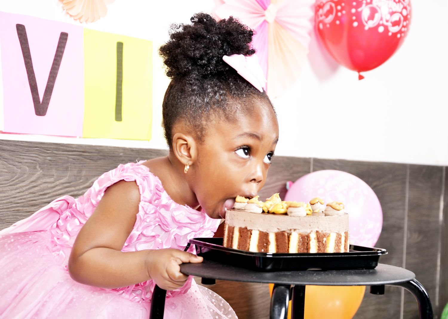 A celebratory birthday scene with pink balloons and cake.