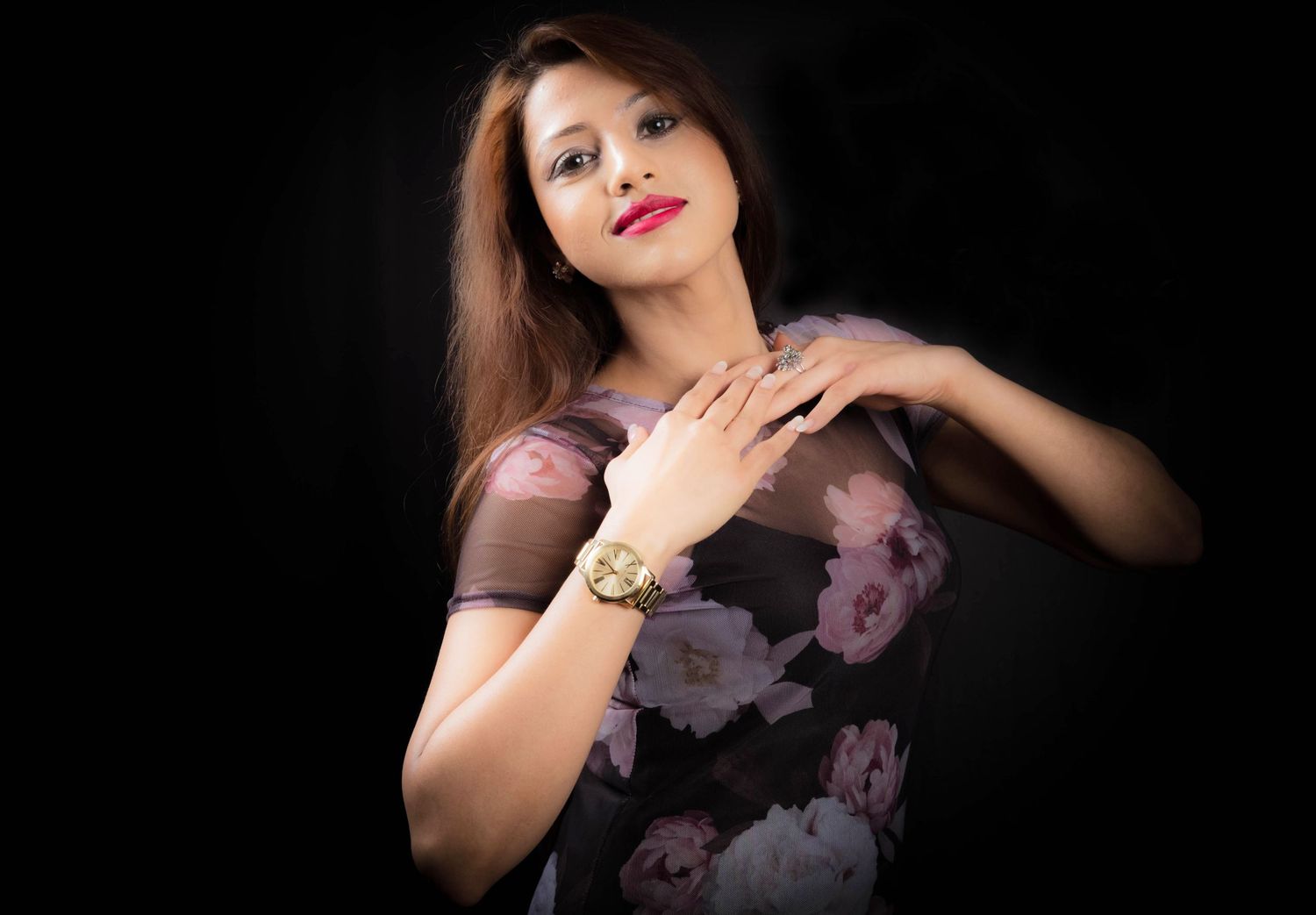 Person poses dramatically against dark background wearing floral print top.