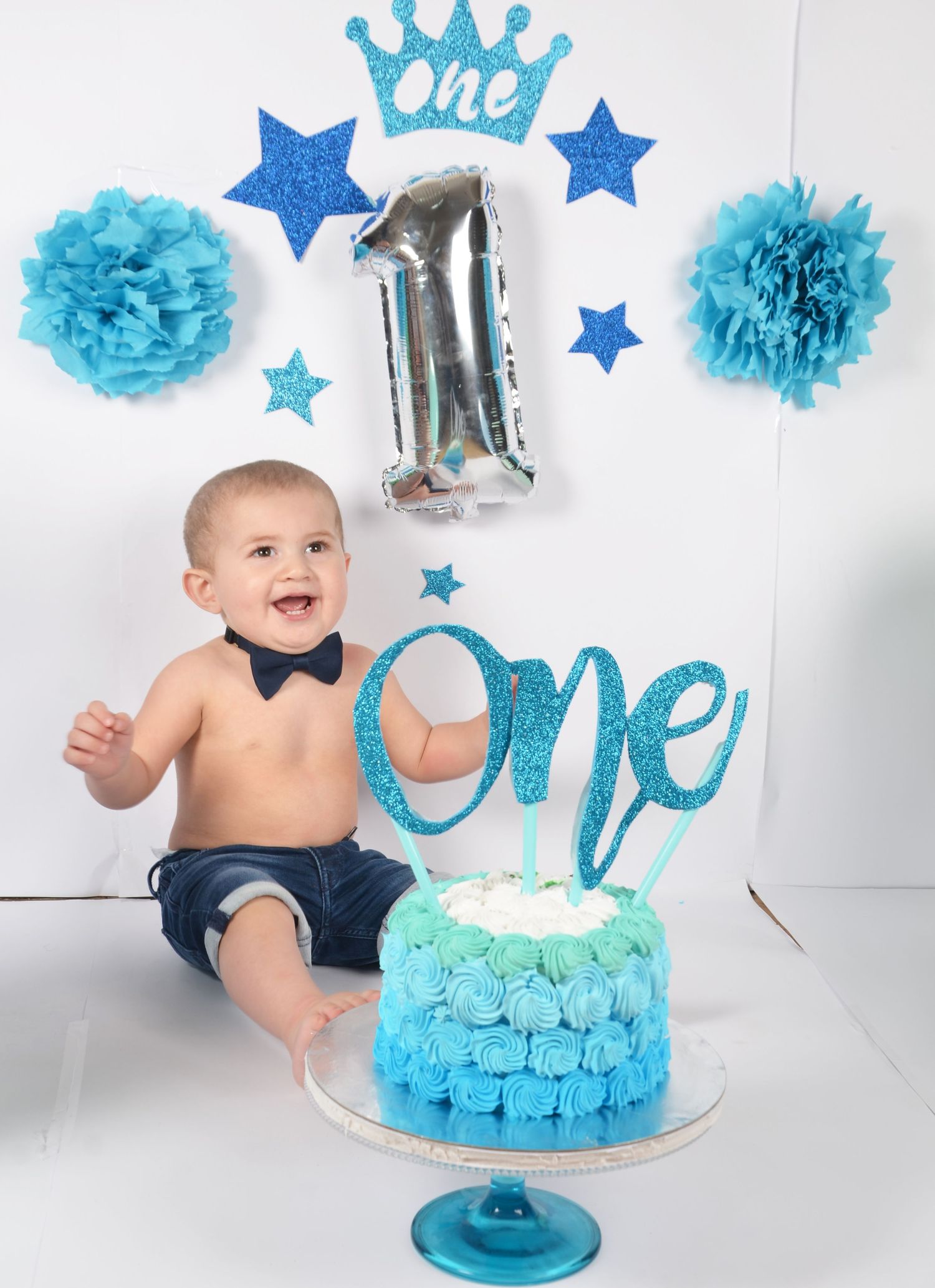 First birthday cake smash setup with blue stars, crown decorations and turquoise cake.