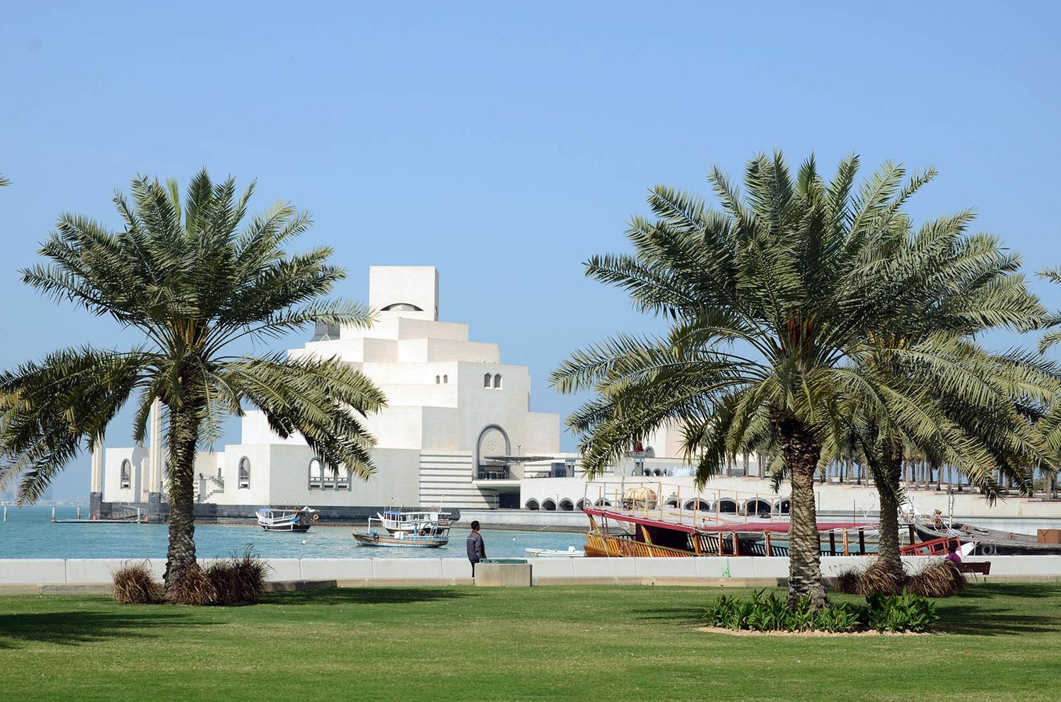 Museum of Islamic Art in Doha Qatar with palm trees and waterfront view.